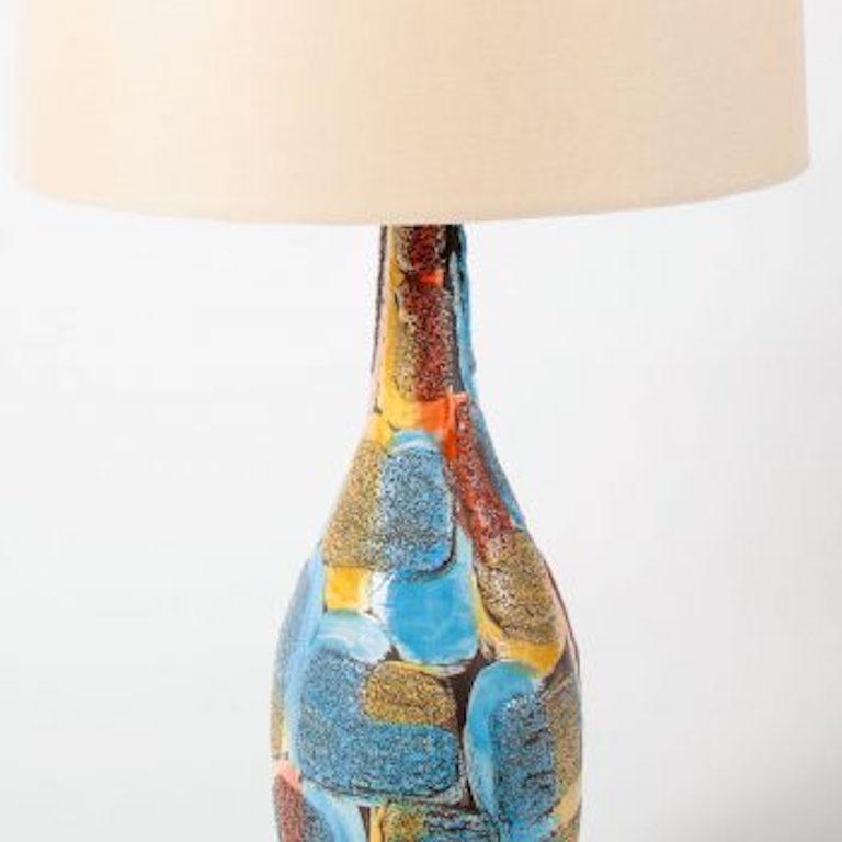 Volcanic glazed ceramic lamp made in Italy. Bright blue, ochre, and burnt orange overall patchwork design. Textured surface. Wooden base in a dark walnut finish. Rewired with a braided nylon cord. New ecru linen shade.