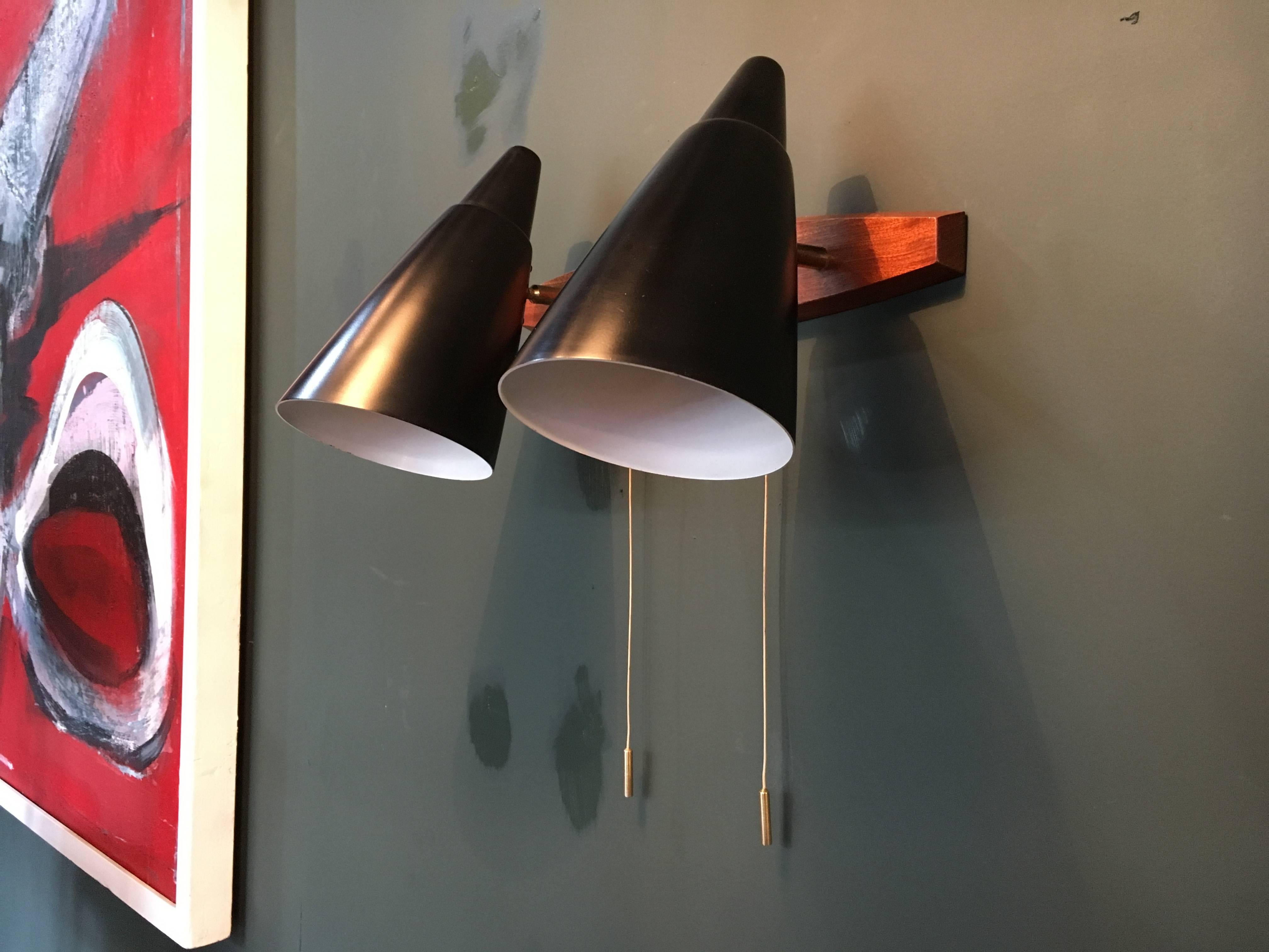 Dual cone midcentury Italian wall lights, dating from the 1950s. These lights are multi-directional and can be individually lit. Satin-matte black cones with white interior on teak wall mount with brass fittings. In superb condition and fully