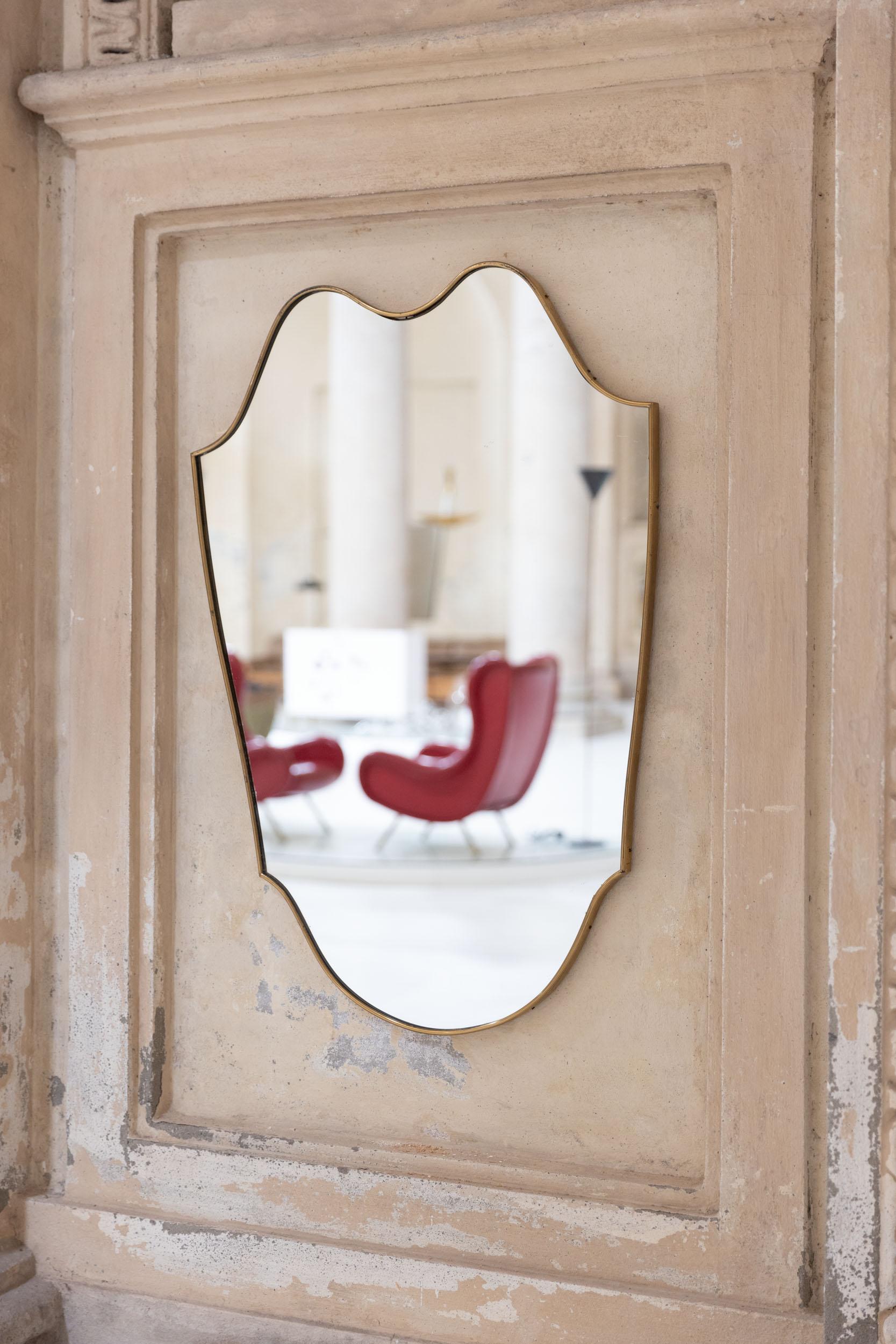 Midcentury Italian wall mirror, elegant brass frame with amazing shape and beautiful vintage patina. 
Excellent condition with original mirror.
Italy, 1950 