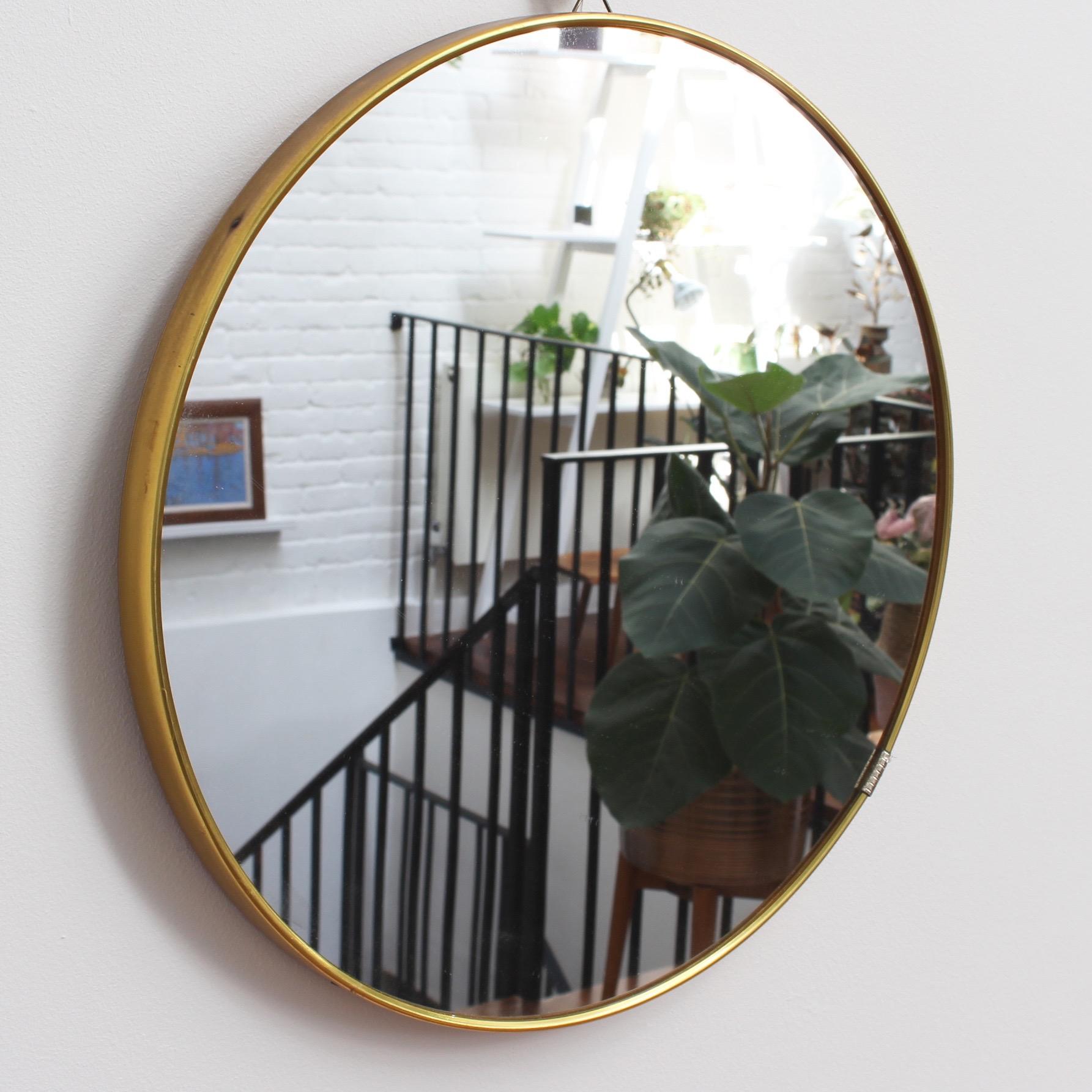 Midcentury Italian wall mirror with brass frame, circa 1950s. The mirror is beautifully circular and so smart with irresistible durability. The effect is elegant and very distinctive in a modern Gio Ponti style. The mirror is in good vintage