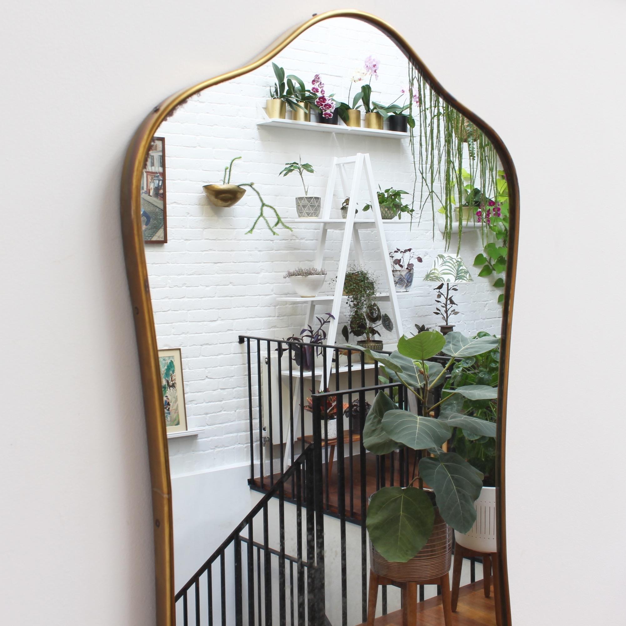 Midcentury Italian wall mirror with brass frame, circa 1950s. The mirror is classically-shaped - very elegant and distinctive in a modern Gio Ponti style. This mirror is in good vintage condition. There are some evident but characterful blemishes on