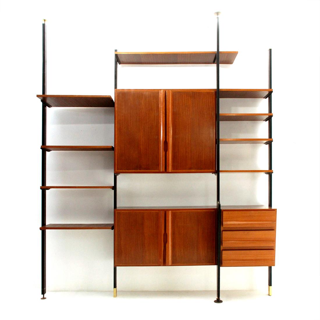 Italian manufacture wall unit produced in the 1950s.
Structure and uprights in black painted metal, terminals and feet in brass.
Shelves and storages in veneered wood.
Storage compartments and chest of drawers with carved handles.
Fair general