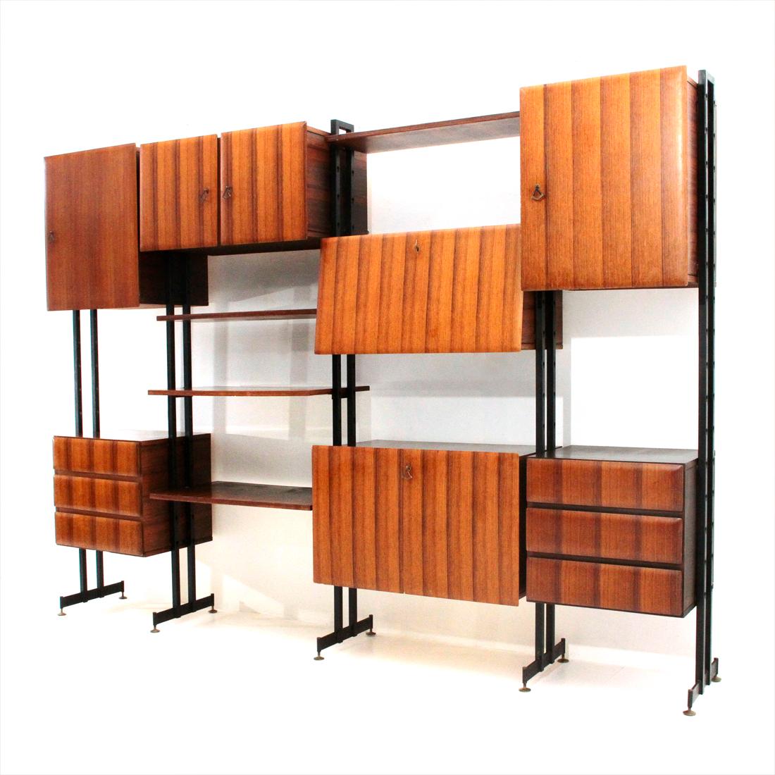 Italian manufacture library produced in the 1950s.
Uprights in black painted metal with brass feet adjustable in height.
Container modules in veneered wood.
Front panels and drawers with tapered edges.
Interior shelves in veneered wood.
Bar