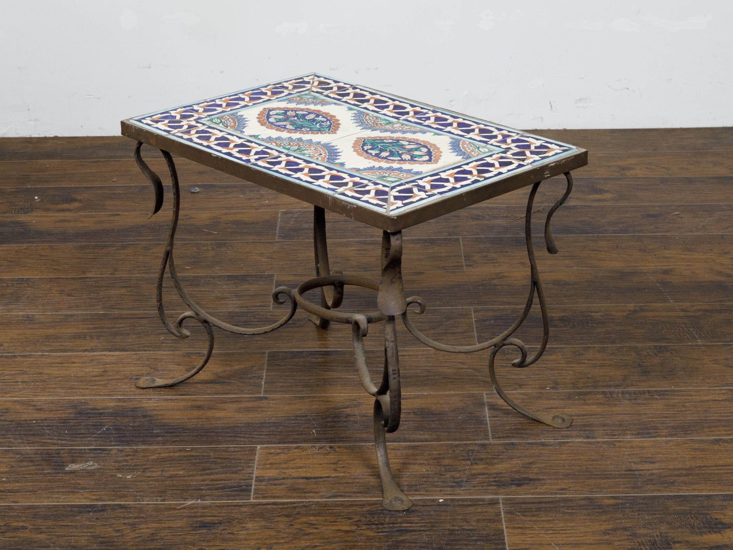 An Italian wrought-iron coffee table from the Midcentury period, with tile top and scrolling base. This Italian Midcentury wrought-iron coffee table presents a delightful amalgamation of classic design and vibrant aesthetics, making it a striking