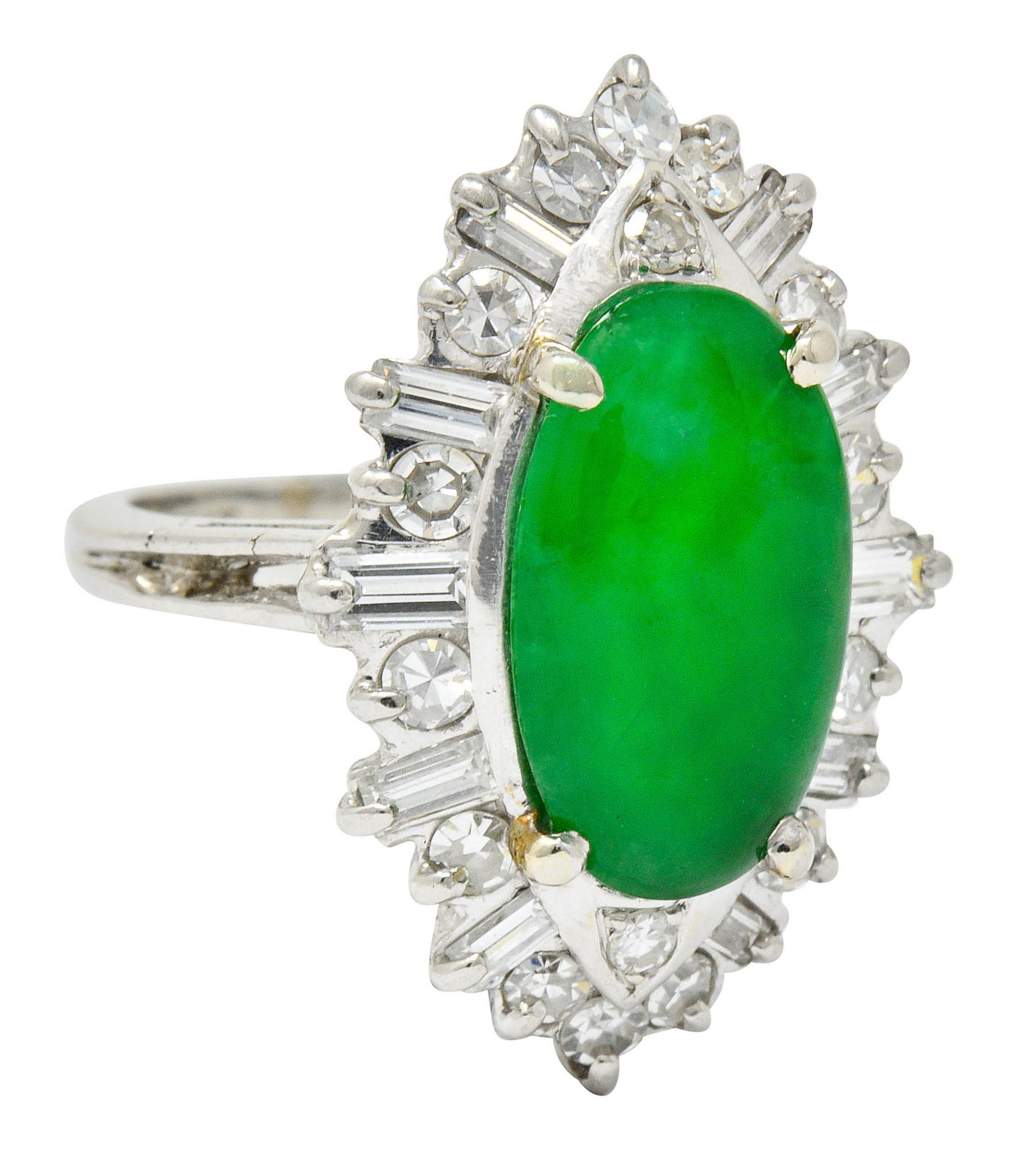 Cluster style ring centering an oval jadeite cabochon measuring approximately 14.3 x 8.3 mm

Bright in color, translucent green to dark green, with no indications of impregnation; type A jadeite jade

Surrounded by a diamond halo of baguette and