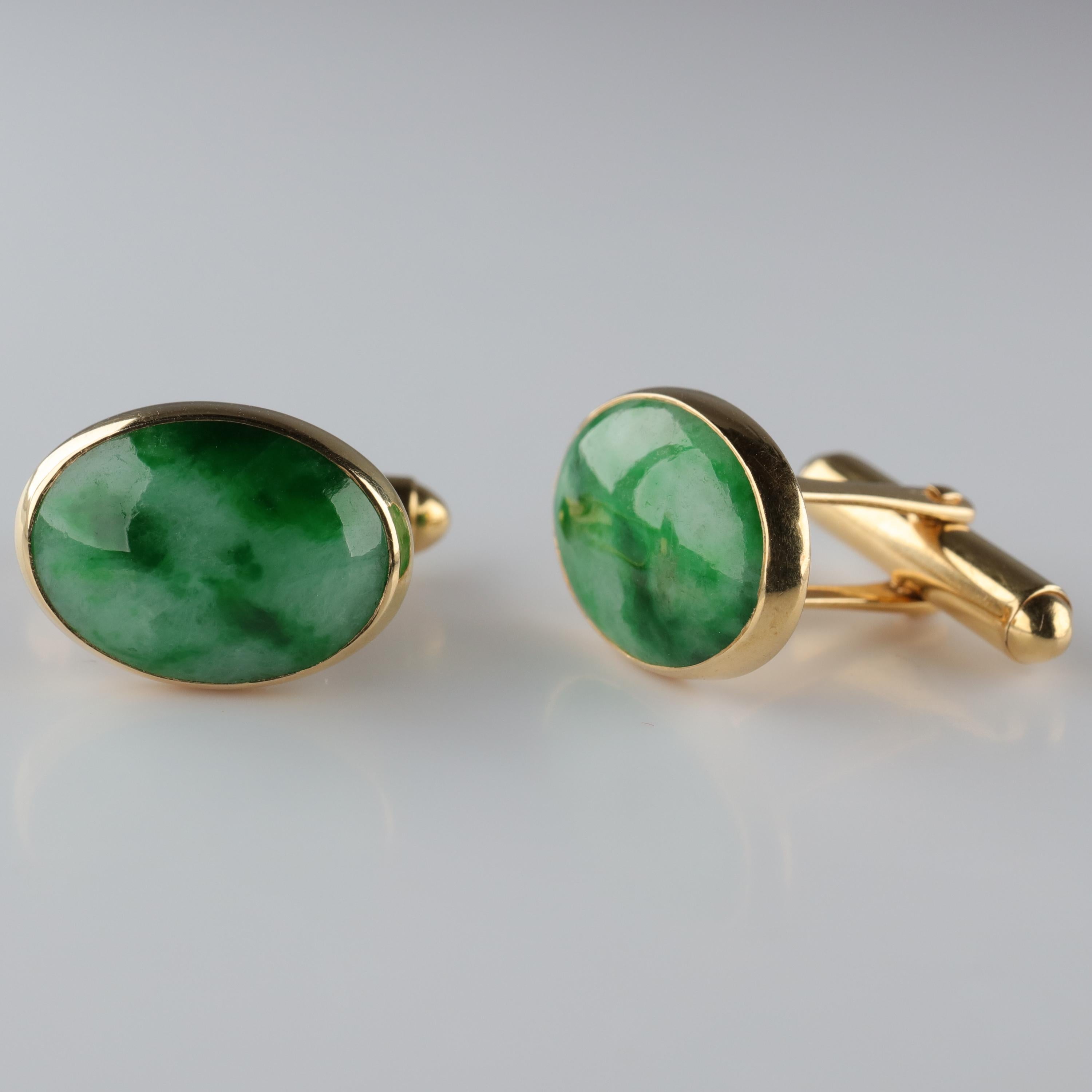 These sleek, timeless mid-century cufflinks feature a pair of natural and untreated mottled jadeite jade cabochons with a pale green body color streaked with slender ribbons of vibrant emerald green. 
