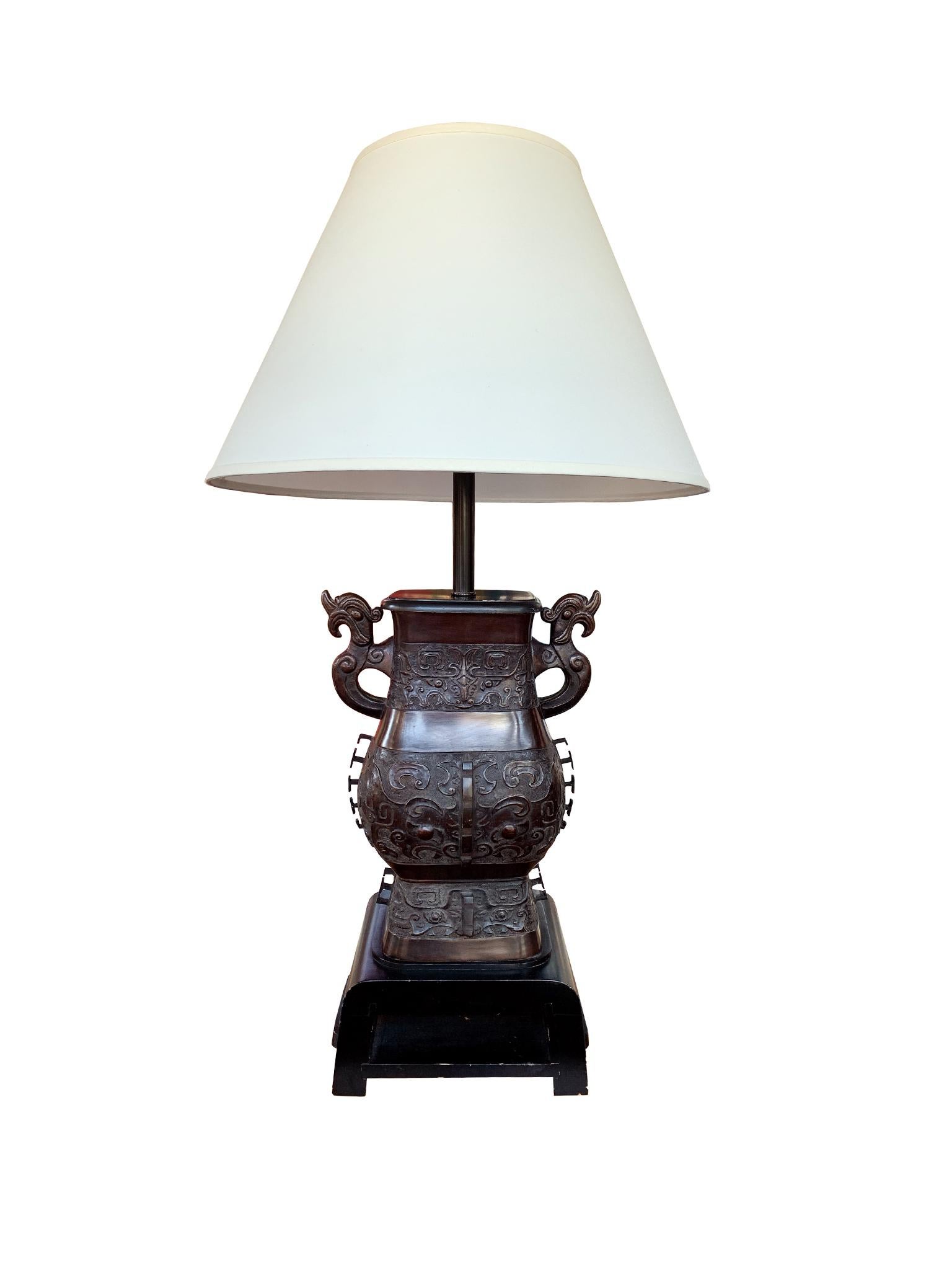 This James Mont table lamp is comprised of a cast bronze body with wood base and top. It was made in the Mid-20th Century. Like Mont's other eccentric designs, the lamp brings together his various stylistic influences. Floral and geometric motifs