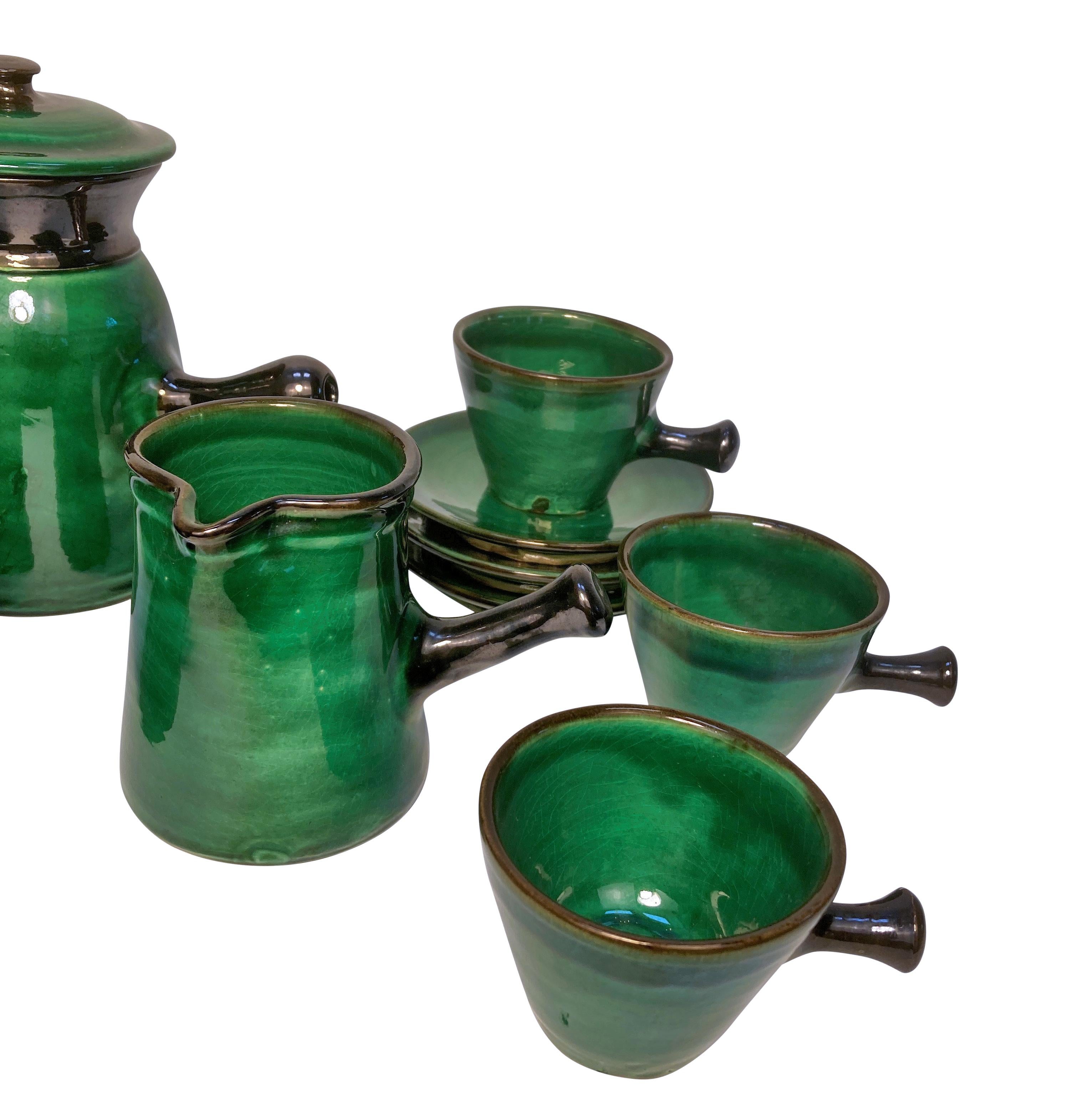 Juego de té japonés de mediados de siglo, compuesto por seis tazas, seis platillos, una tetera, leche y azúcar en un precioso esmalte verde esmeralda.

Medidas: 16 cm de alto x 18 cm de ancho x 14 cm de fondo (tetera)