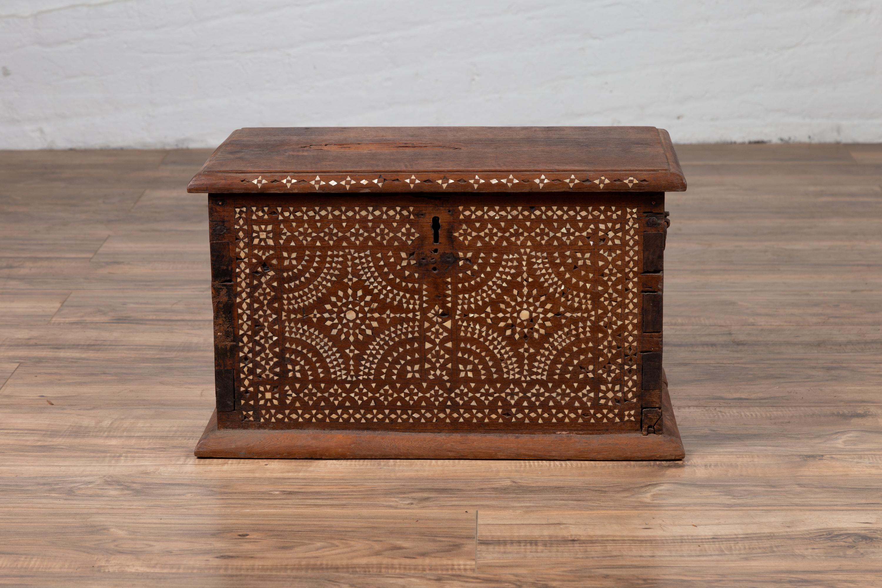 A vintage Javanese wooden trunk from the mid-20th century, with mother of pearl inlay. Born on the Island of Java during the midcentury period, this charming wooden trunk features a rectangular lid with beveled edges sitting above a beautiful body