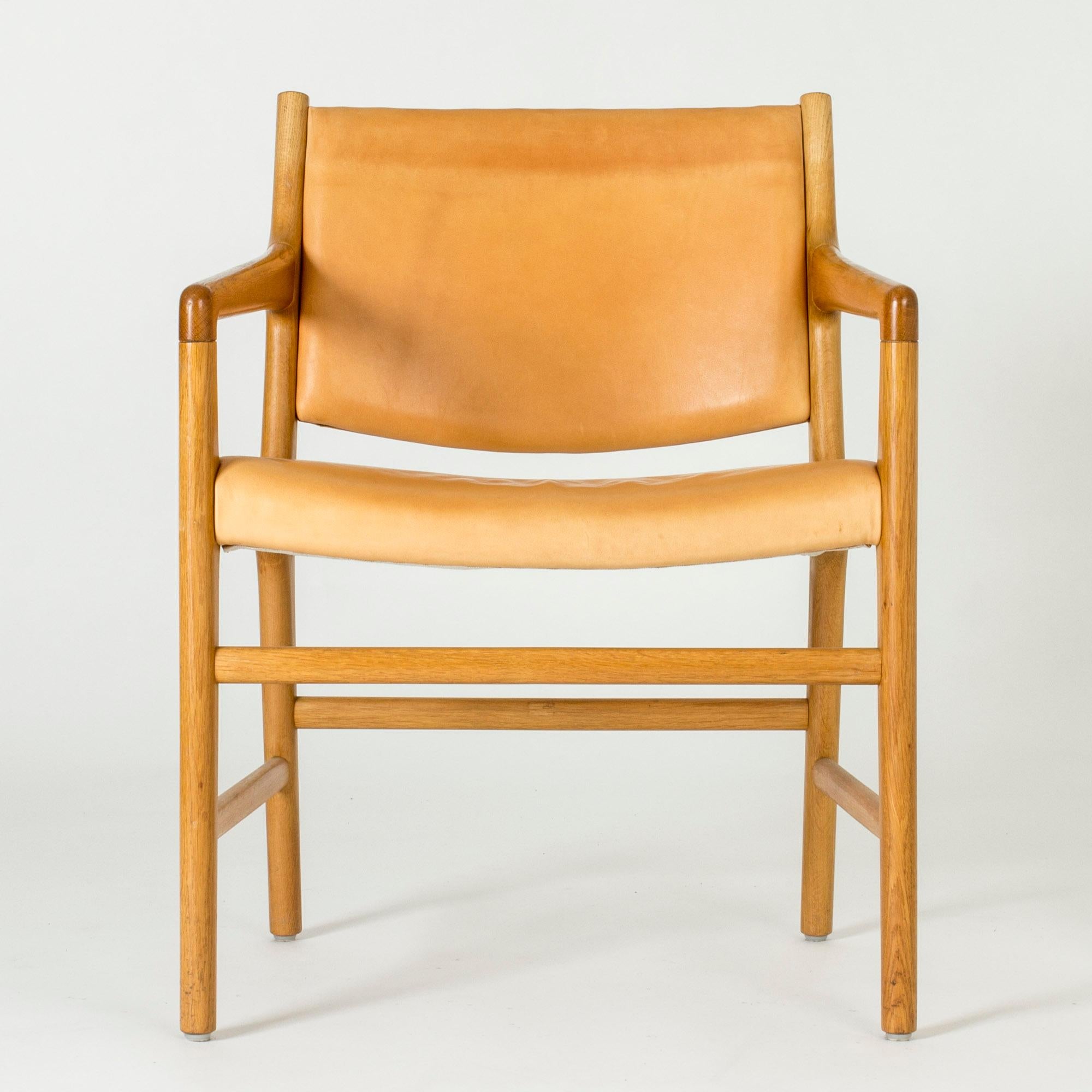 Elegant “JH 507” armchair by Hans J. Wegner, made with an oak frame and natural leather seat and back.