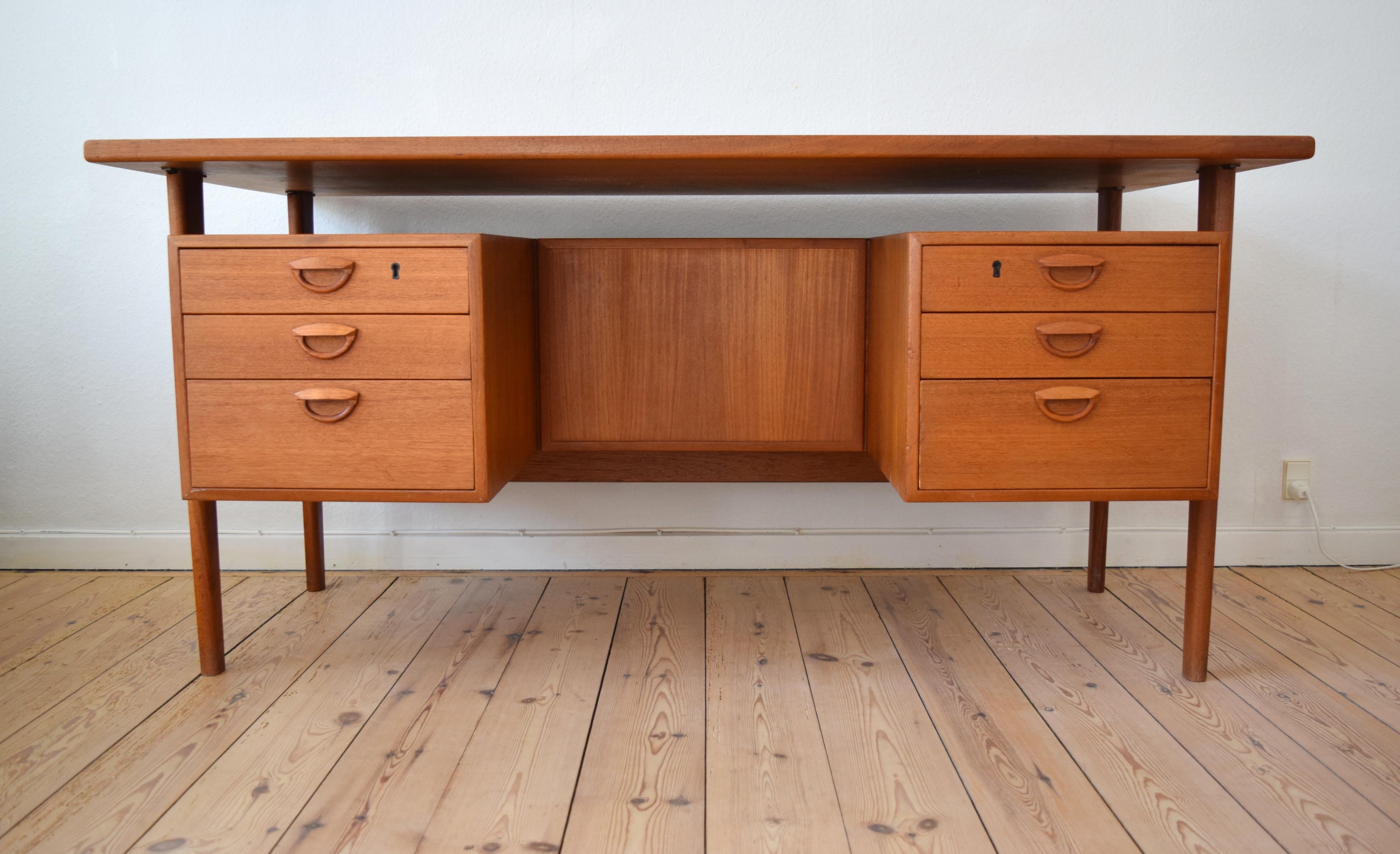 Danish executive teak desk designed by Kai Kristiansen by Feldballes Møbelfabrik as model FM60 in 1958. This freestanding desk features a floating top and six drawers (two lockable) on the front. There are also three compartments on the back. Carved