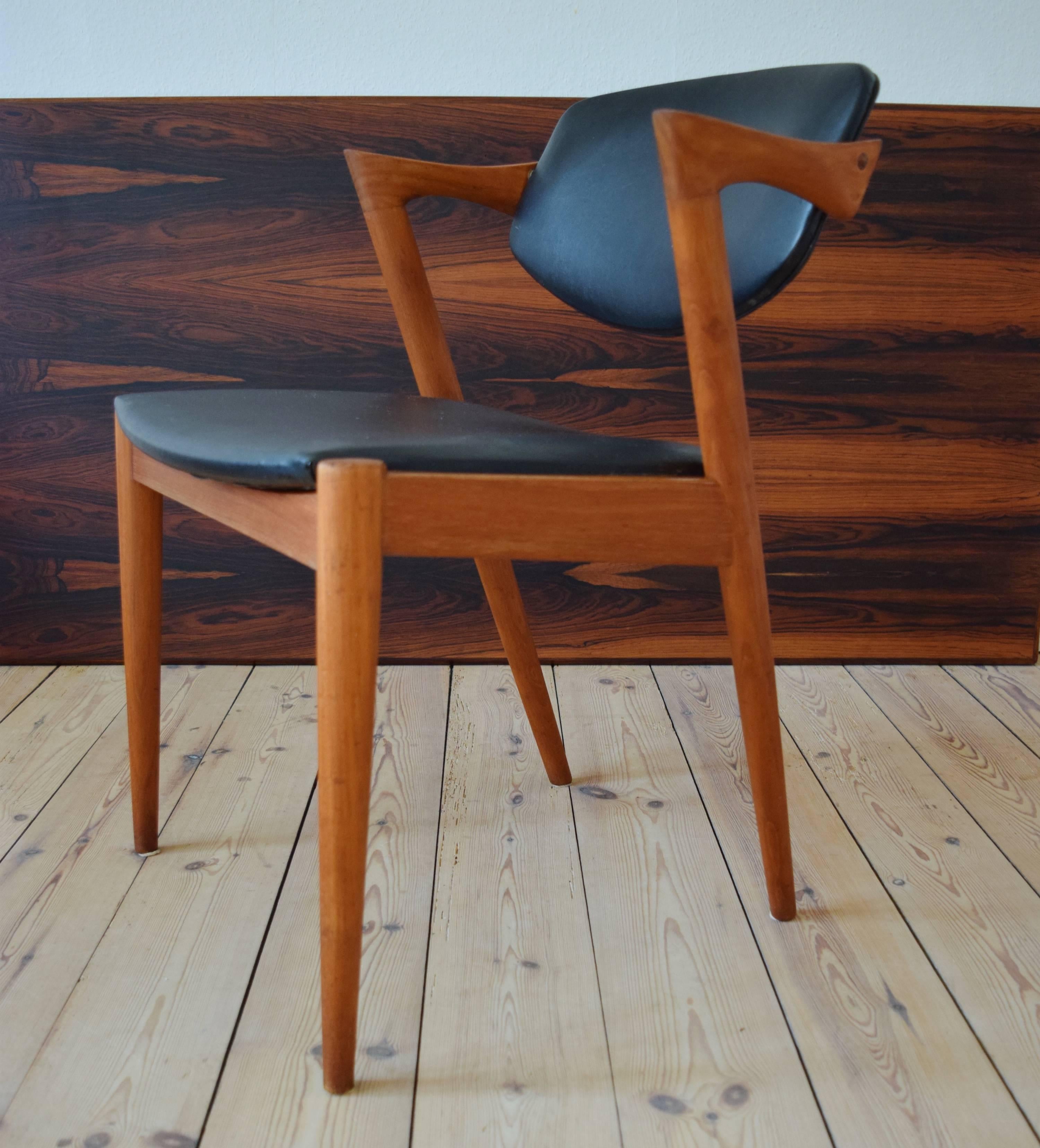 Kai Kristiansen model 42 teak dining chair, manufactured by Schou Andersen in the 1960's. This chair is covered in the original black skai. Chair frames have been re-finished, cleaned and oiled. Some small marks here and there commensurate with age,
