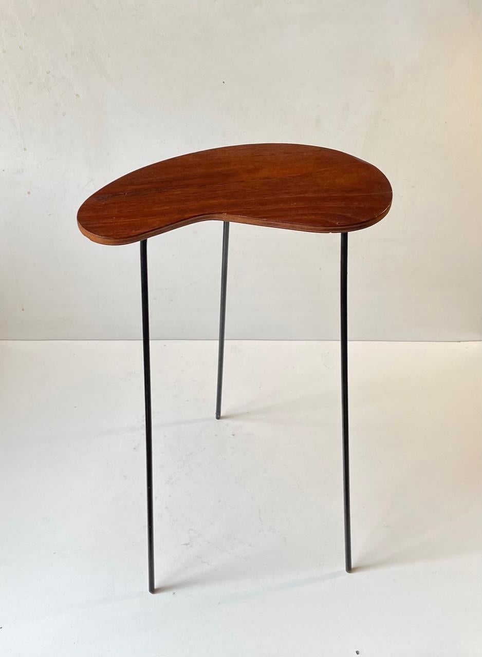 A small side, lamp, candle or plant table in teak and black lacquered steel. A very graphic look due to its simple construction and 'light' appearance. The kidney shaped tabletop has been cleaned and oiled. Measurements: H: 41 cm, W: 29 cm, Dept: