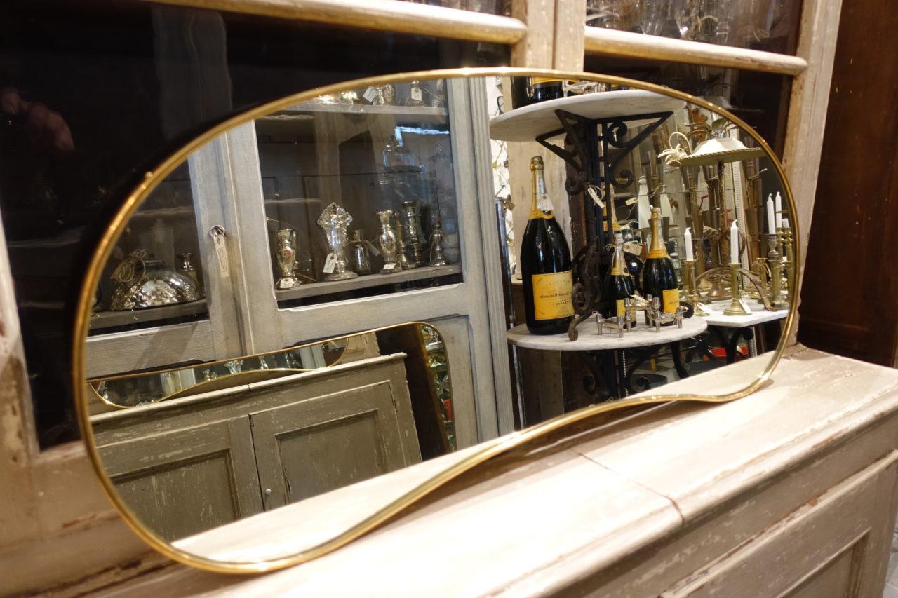 Elegant and stylish kidney shaped Italian brass mirror. Midcentury, and attributed in style to the 1950s designer Gio Ponti. Original glass, and comes with wall attachment chain.
