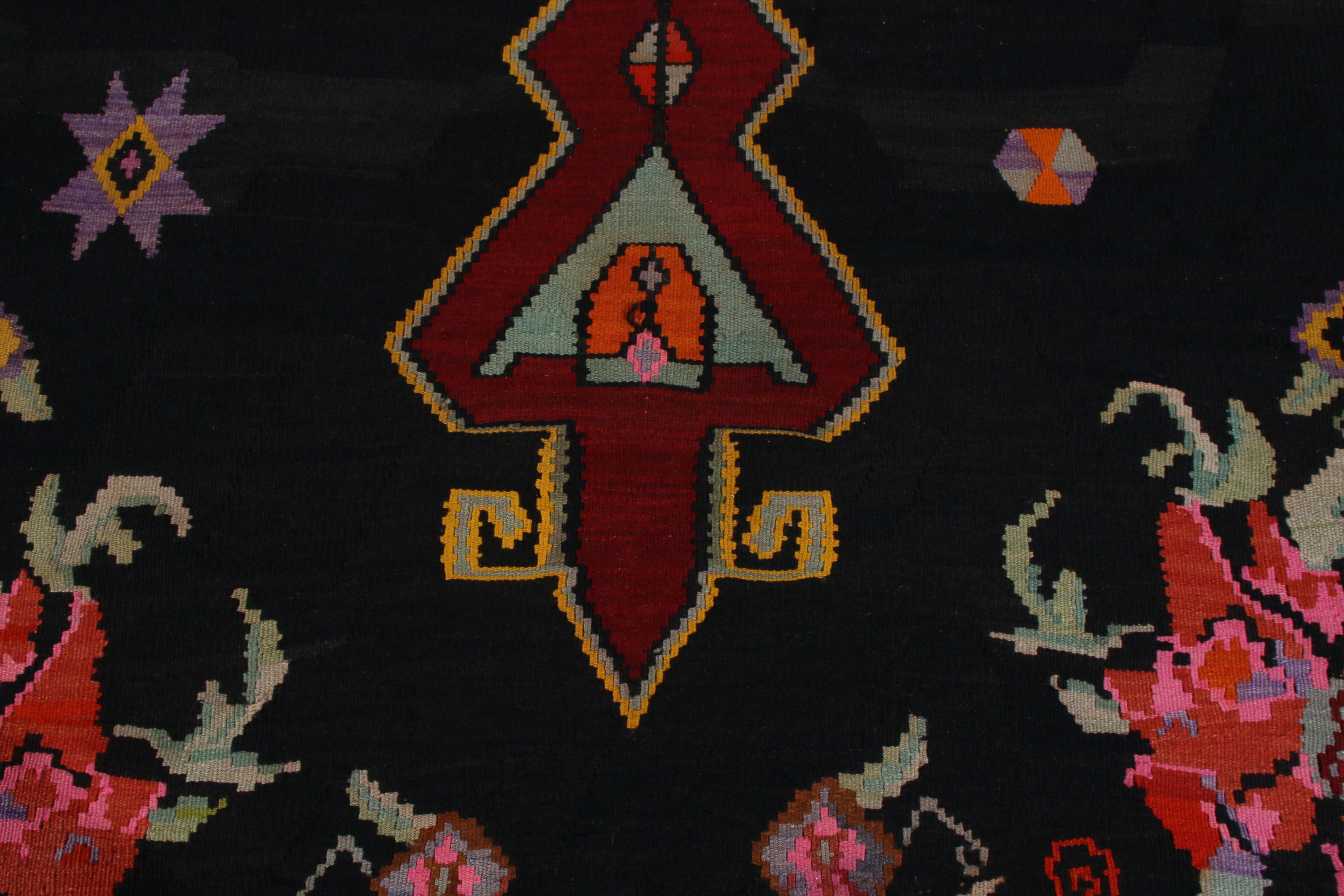 Realizzato a mano in lana intorno al 1950-1960, questo tappeto Kilim vintage a trama piatta è stato creato in Turchia. Questo kilim della metà del secolo scorso presenta un motivo a medaglione rosso che circonda un singolo fiore in rosa, viola e