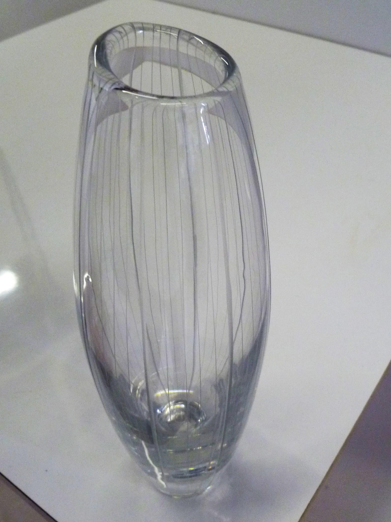 Striped Mid-Century Modern engraved mouth blown clear glass vase by Vicke Lindstrand, 1904-1983 Sweden, for Kosta in 1956.
In a cylindrical shape with augmented middle and a slanted mouth. The vertical stripes are engraved in a pattern of one thick