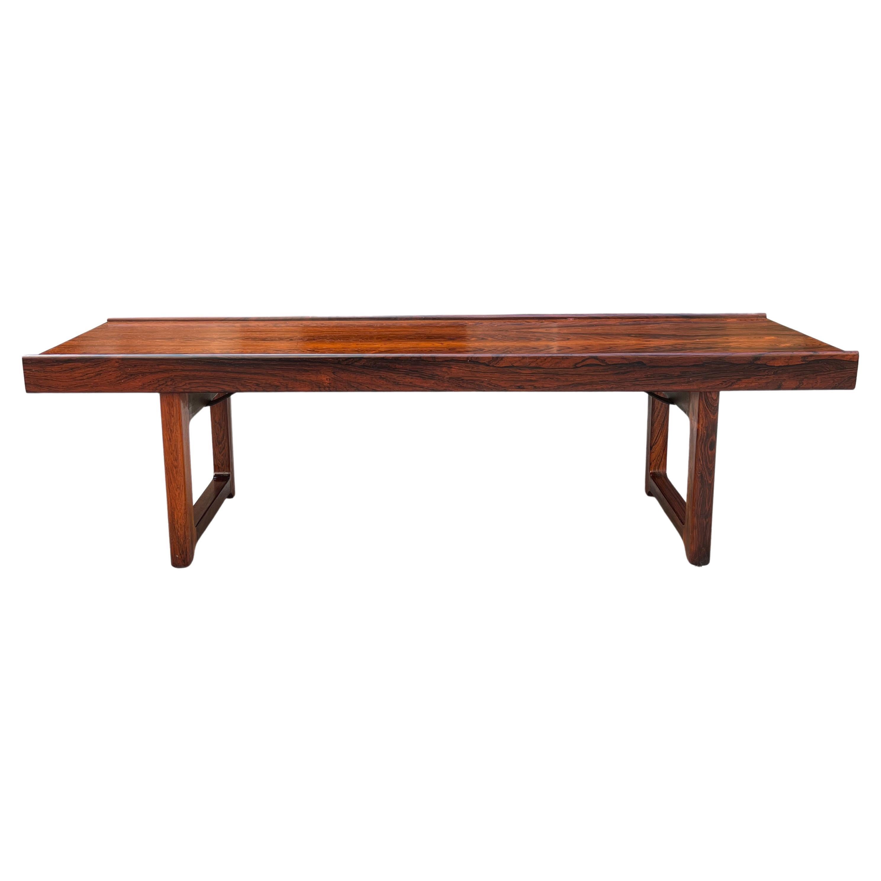 Mid-Century Scandinavian modern low coffee table / bench designed by Torbjørn Afdal for Bruksbo, Norway. This piece displays rich wood grains and sculpted edges. The perfect fit for an entryway piece or bedroom seating. A sleek rosewood “Krobo”