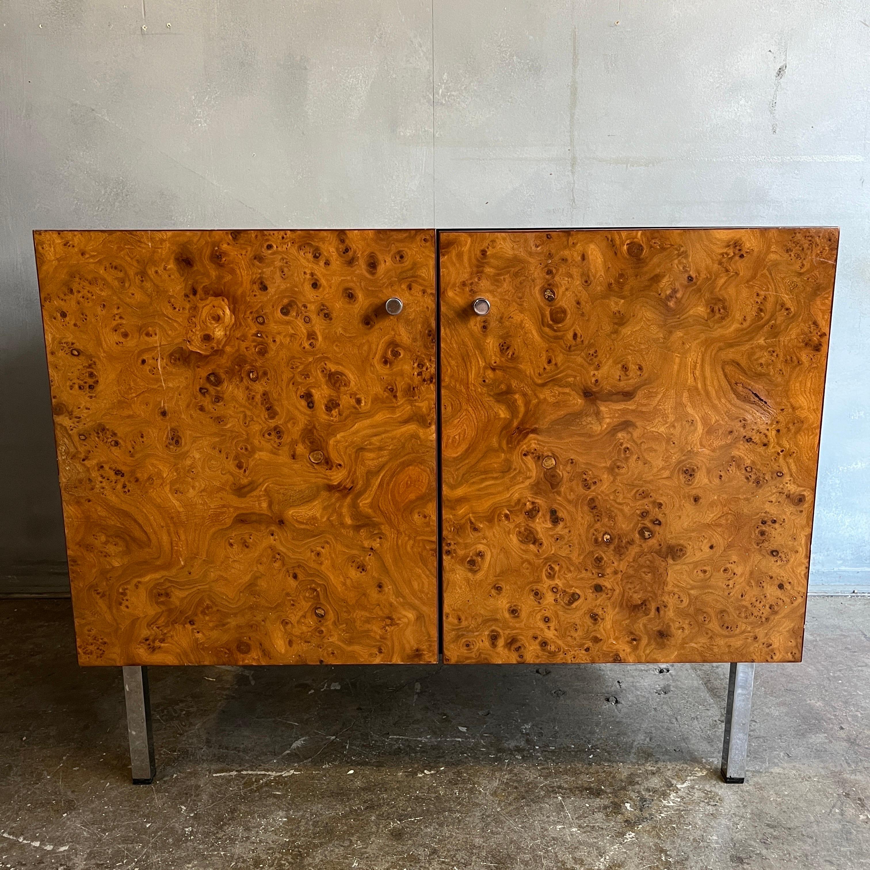 Petite midcentury cabinet or credenza with gorgeous highly figurative olive burl wood fronts resting on chromed square legs. Sides are in black lacquer. Inside reveals an adjustable shelf. Striking piece.