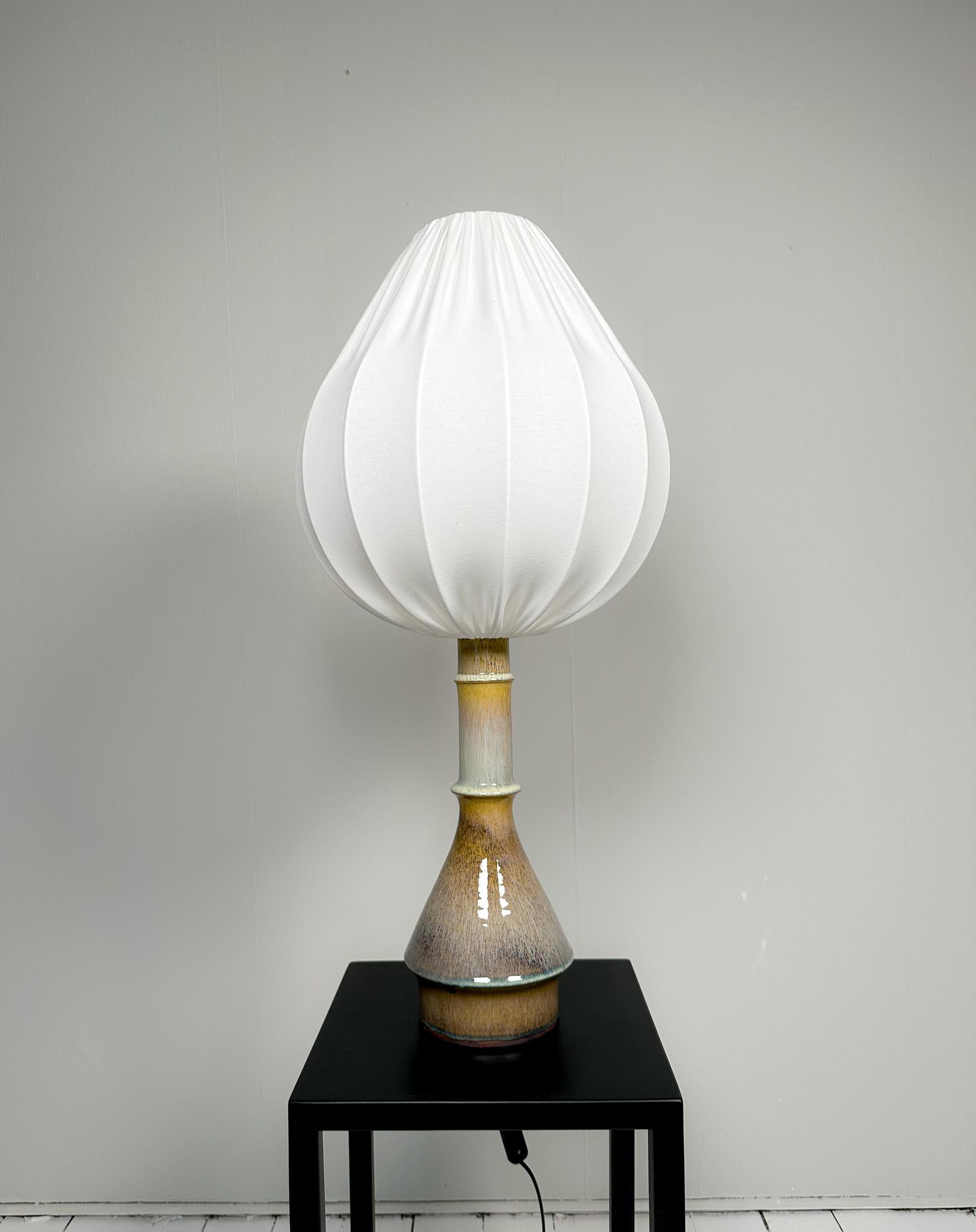 Lampe de table unique en son genre, en céramique émaillée, du designer Carl Harry Harris Stålhane, fabriquée en Suède pour Rörstrand dans les années 1950.

Le fond circulaire s'associe à la partie supérieure plus petite, le tout combiné à une