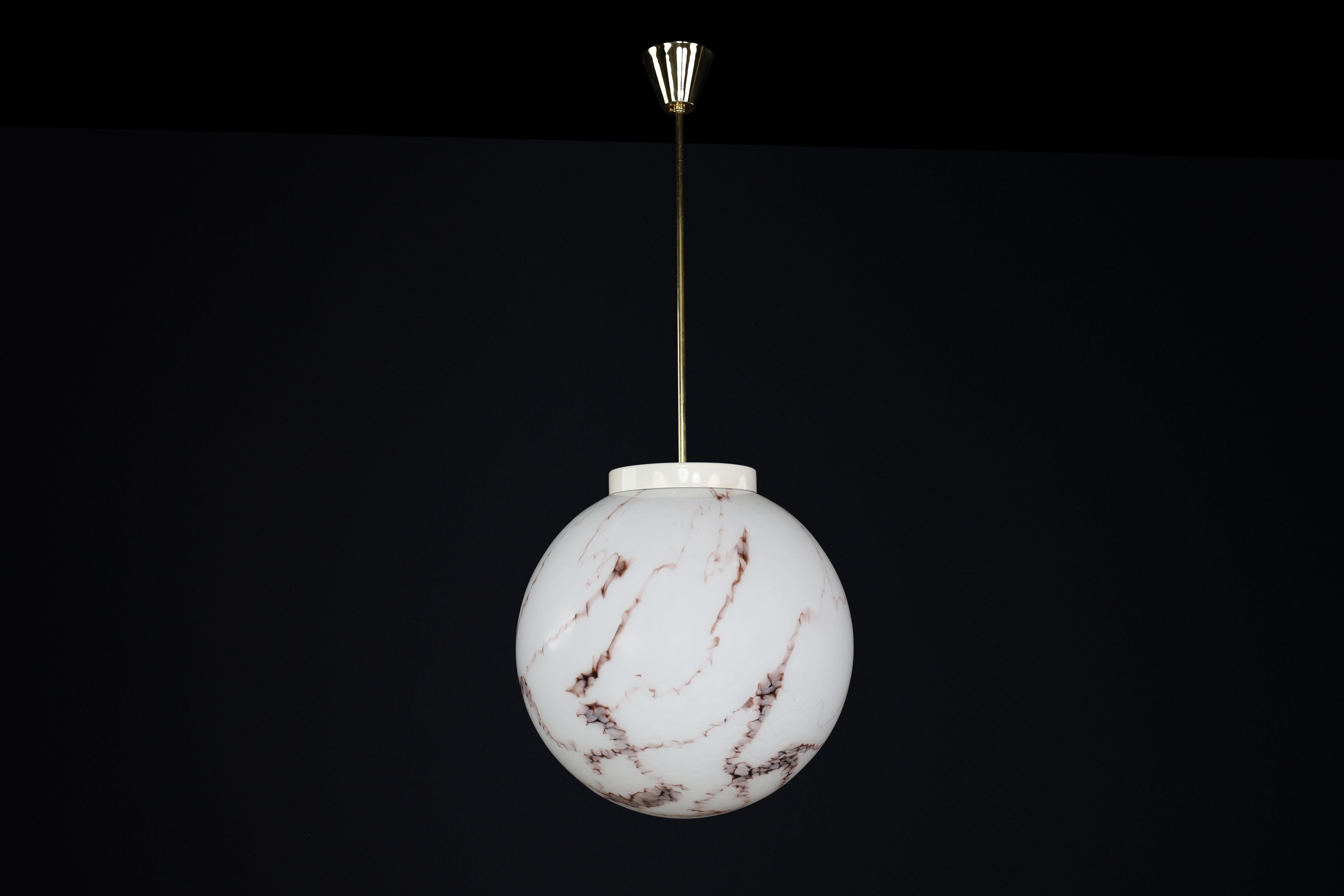 Midcentury Brass and Marble Opaline Glass Pendant, Praque 1950s 

This midcentury pendant is a versatile piece that can enhance the ambiance of any room. Its brass frame and marble opaline glass globe, resembling expressive veins, create a unique