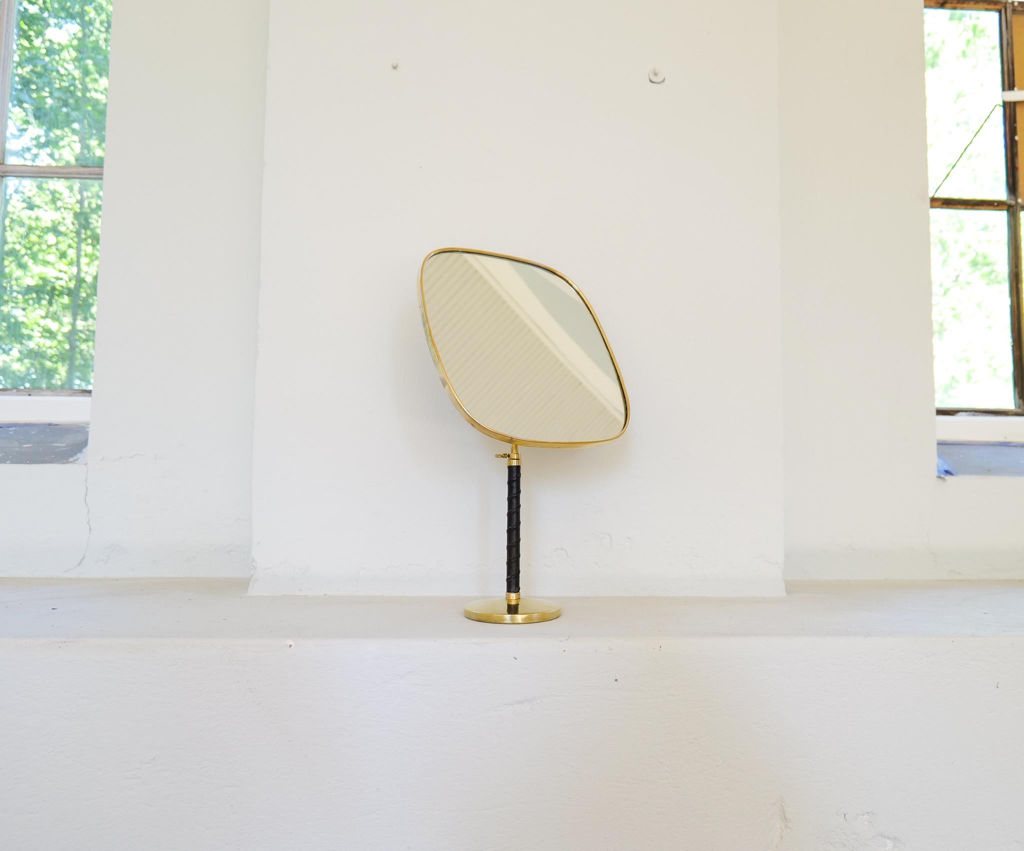 This Large and sculpture table mirror was designed by David Rosén for high-end department stores Nordiska Kompaniet. 
The mirror has very generous proportions and adjustable height that can vary from 48cm to 64 cm. 
Brass and leather details