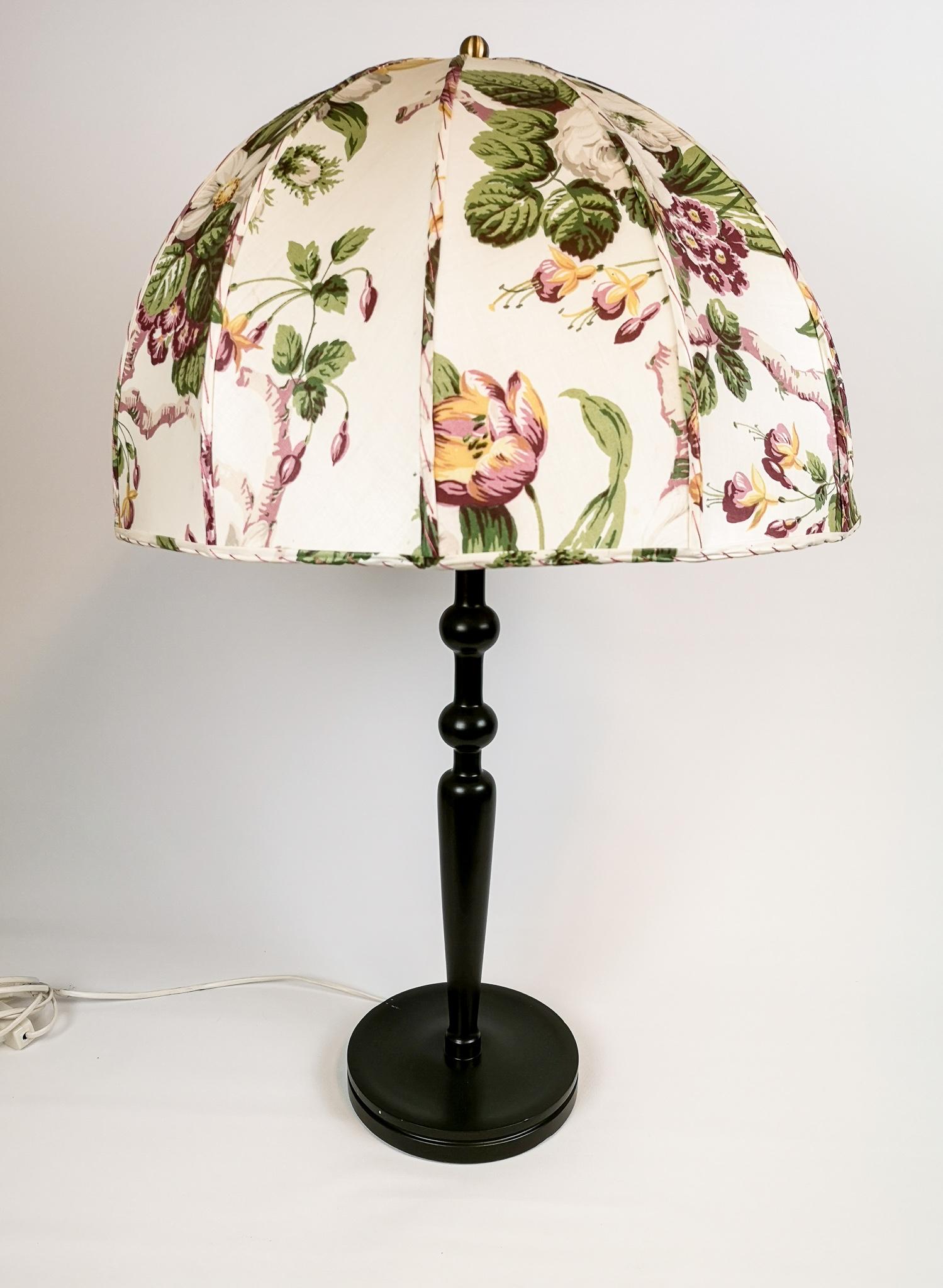 Wonderful large table lamp produced for Svenskt Tenn and designed by Josef Frank.
The base is made of painted wood dark green. The original shade handmade with different flower pattern. 

Nice original condition. Some stains on shade and