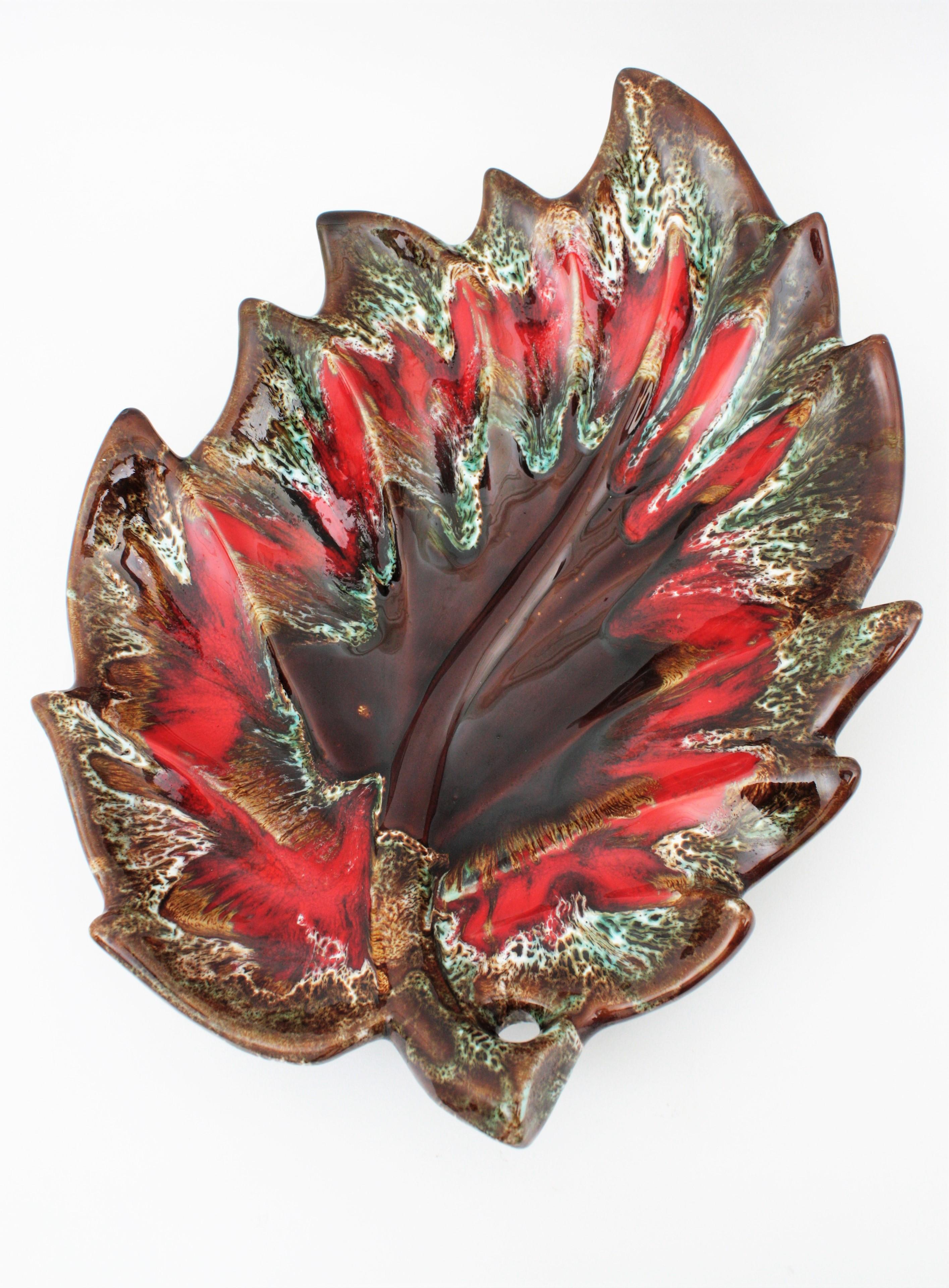 Impressive and colorful extra large leaf shaped glazed ceramic platter, serving tray or centerpiece manufactured by Vallauris. France, 1950-1960s.
Interesting to be used as centerpiece, fruit platter or cakes platter or serving tray. Its large