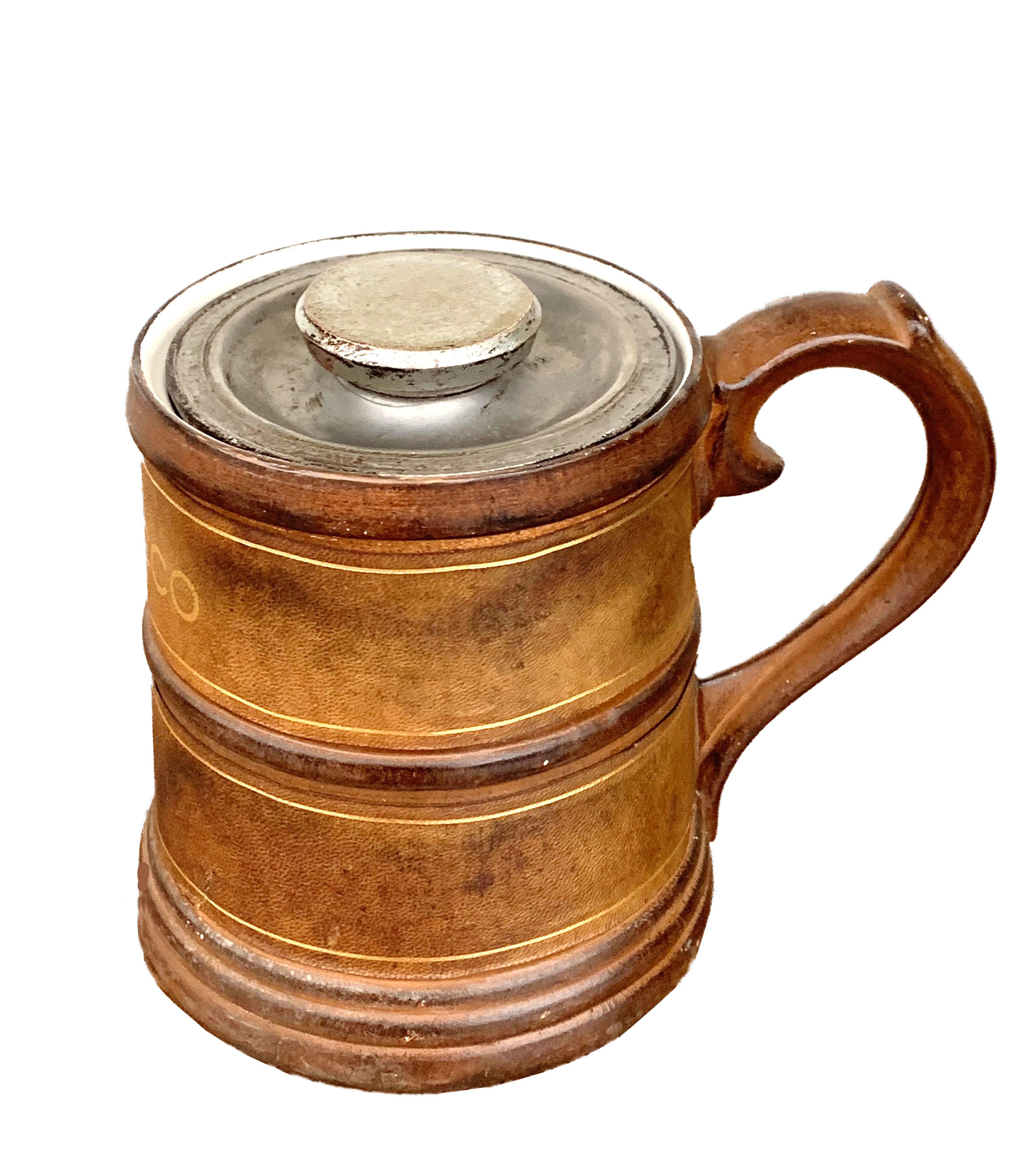 Fantástica tabaquera de cuero y cerámica de mediados de siglo con acabados dorados. Esta asombrosa pieza se fabricó en el Reino Unido durante la década de 1950.

El elemento más relevante de esta pieza es la decoración dorada del cuero y el