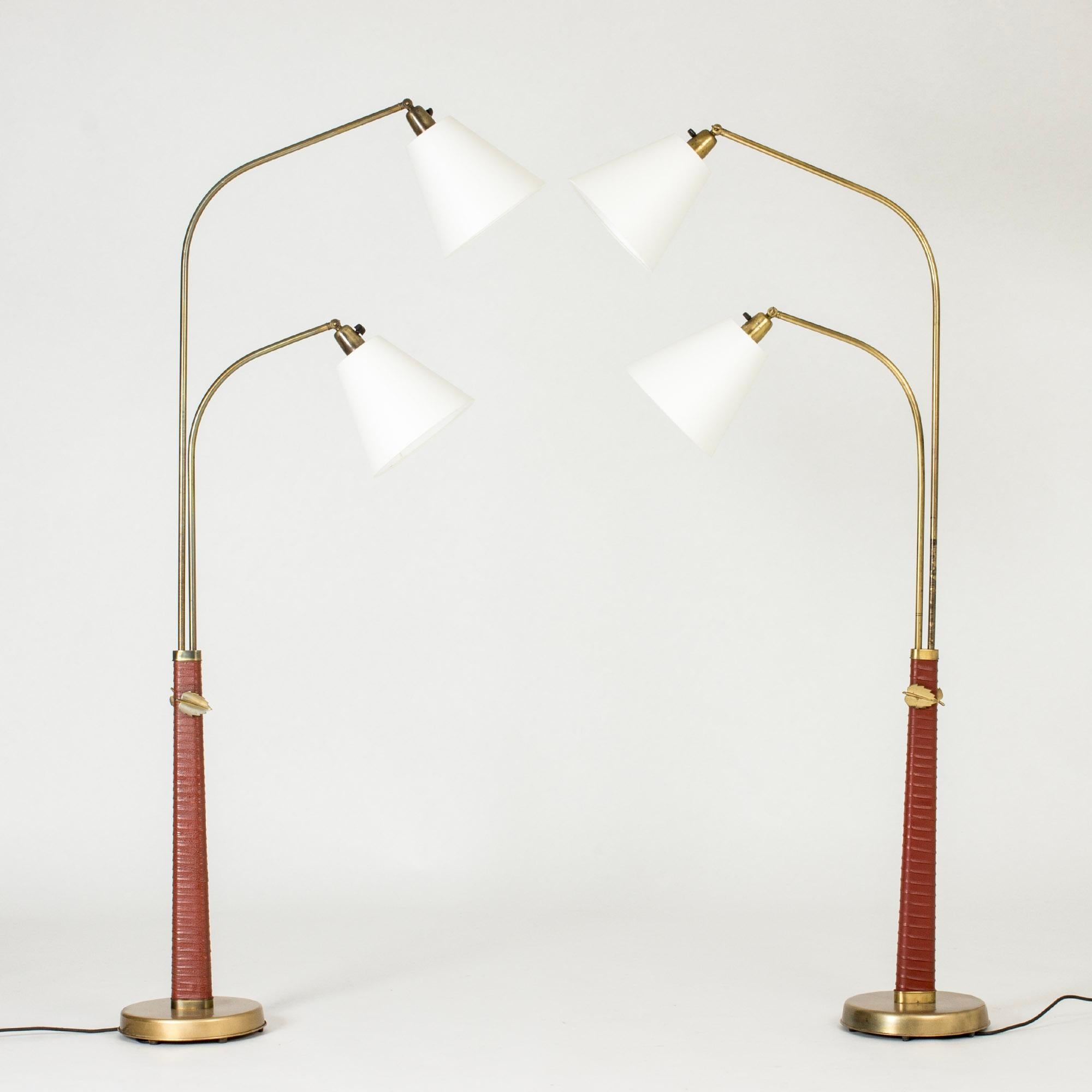 Pair of rare floor lamps by Hans Bergström, early model made in the 1930s. Double brass stems and lamp shades that can be swung into different positions. Tapering bases wound with brown leather. Decorative brass leaves that can be loosened to adjust