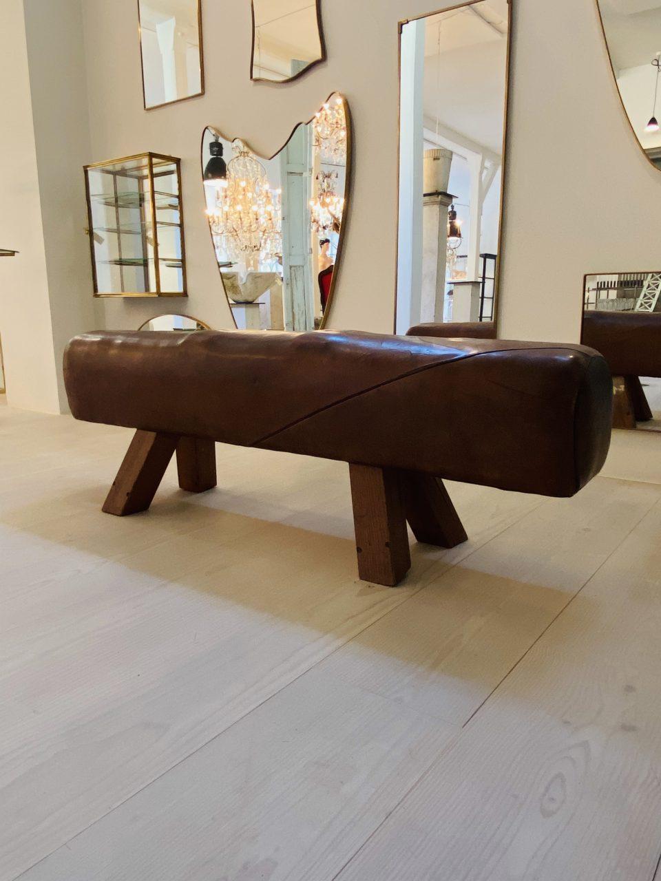 Beautiful vintage elongated school leather bench, which was former gymnastic equipment for spring gymnasts. The base of the masculine look gym horse is made of solid wood and the seat is upholstered with a warm fantastic cognac colored leather with