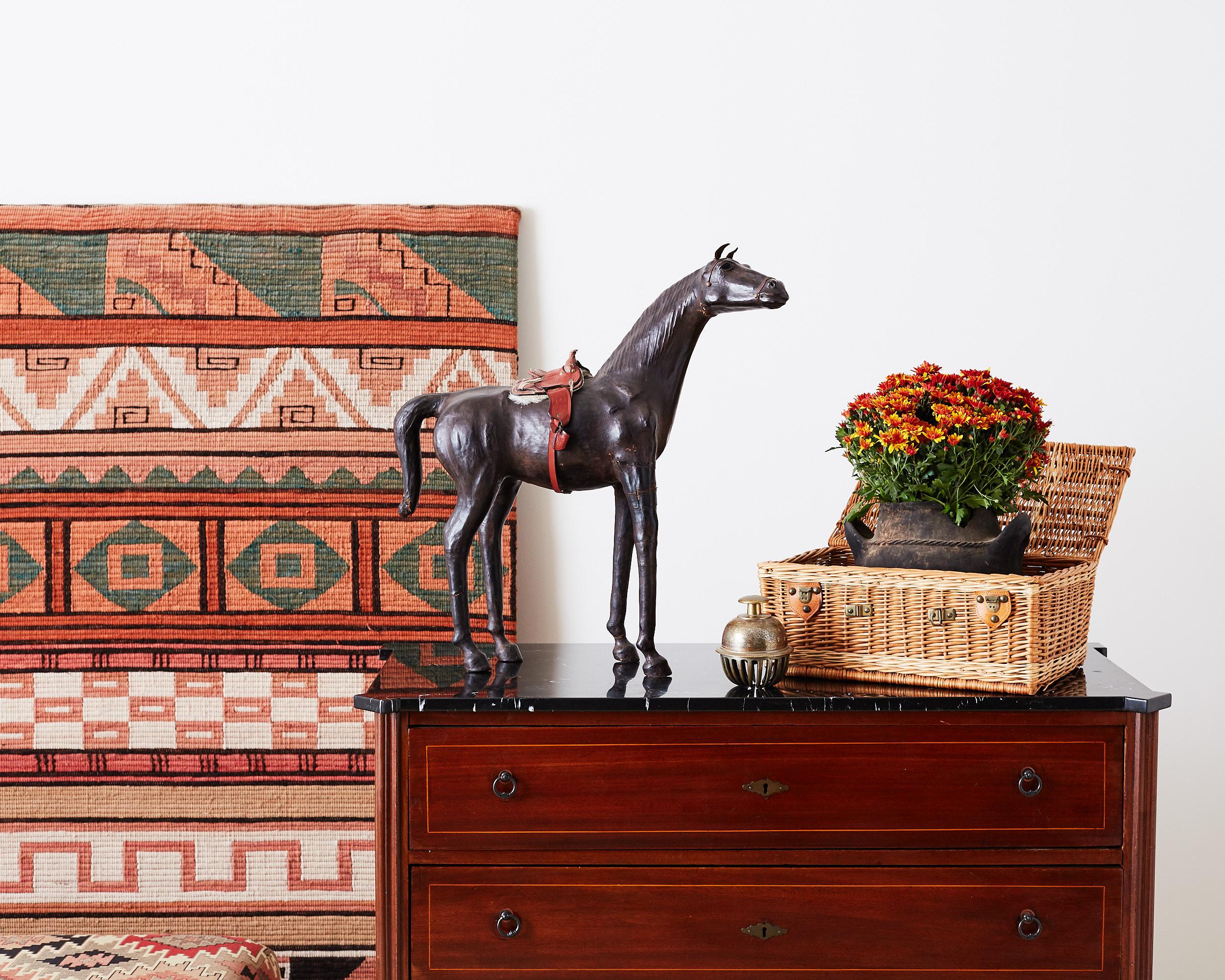 Large Mid-Century Modern handmade leather thoroughbred horse sculpture featuring a red tooled leather saddle with a shearling lining. This lovely horse has a statuesque pose with interesting glass eyes. Beautiful vintage patina on the leather.