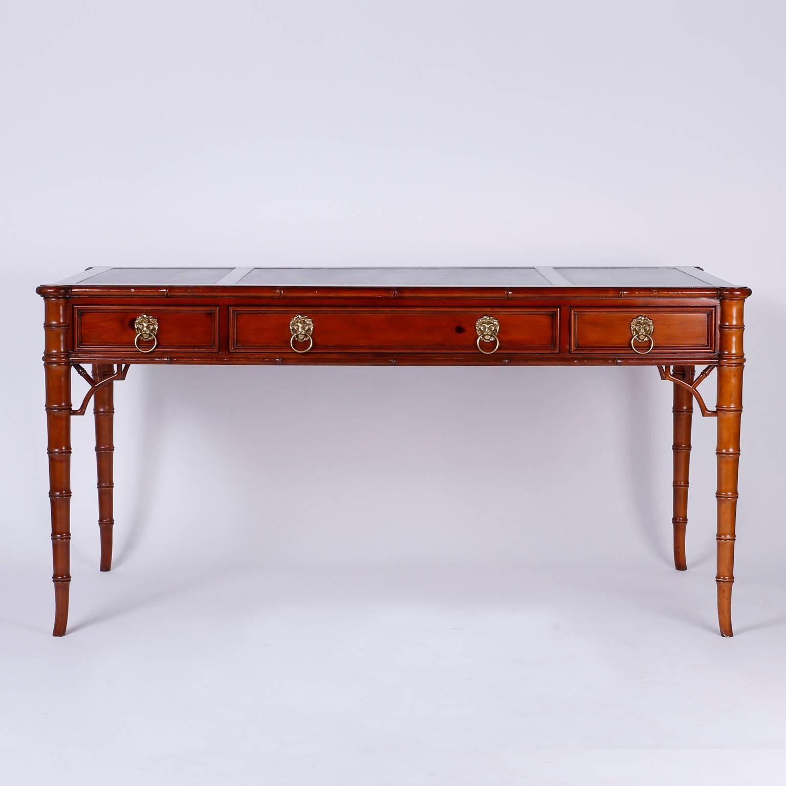 Leather top pine desk or writing table having Chippendale and regency
influences combined with a modern simplicity. The top has three green
leather panels on a three drawer case with lion head pulls, all set on
elegant carved faux bamboo legs