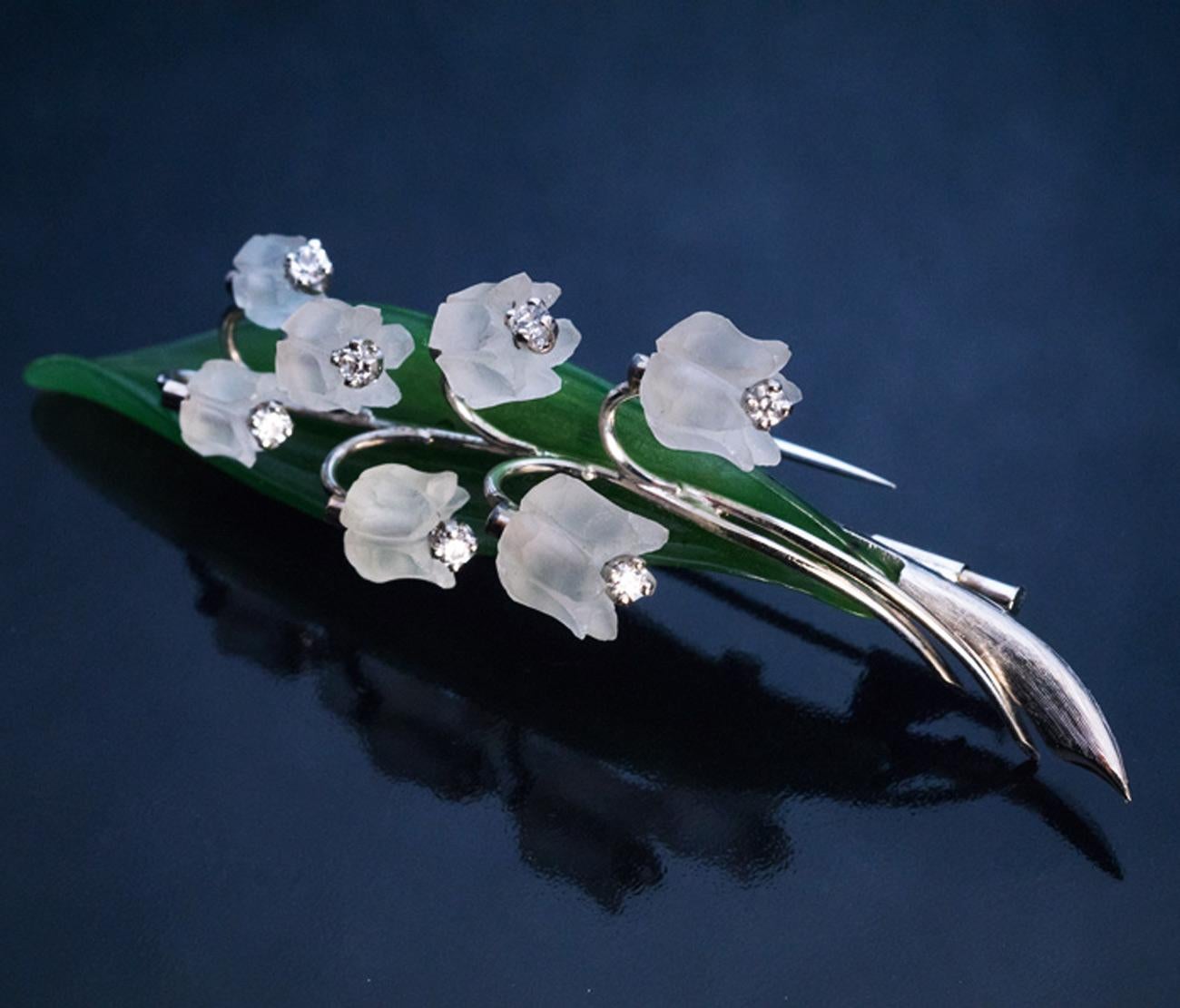 This large realistically modelled 3-dimensional white 14K gold, hand carved nephrite jade and frosted rock crystal lily of the valley brooch / pin was made in Vienna, Austria in the 1950s.

Each flower head is embellished with a diamond.

Marked