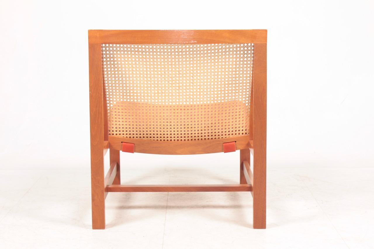 Elegant lounge chair with beech frame and French caning in seat and back. Seat cushion in patinated leather. Designed by Danish architects Johnny Sørensen and Rud Thygesen.