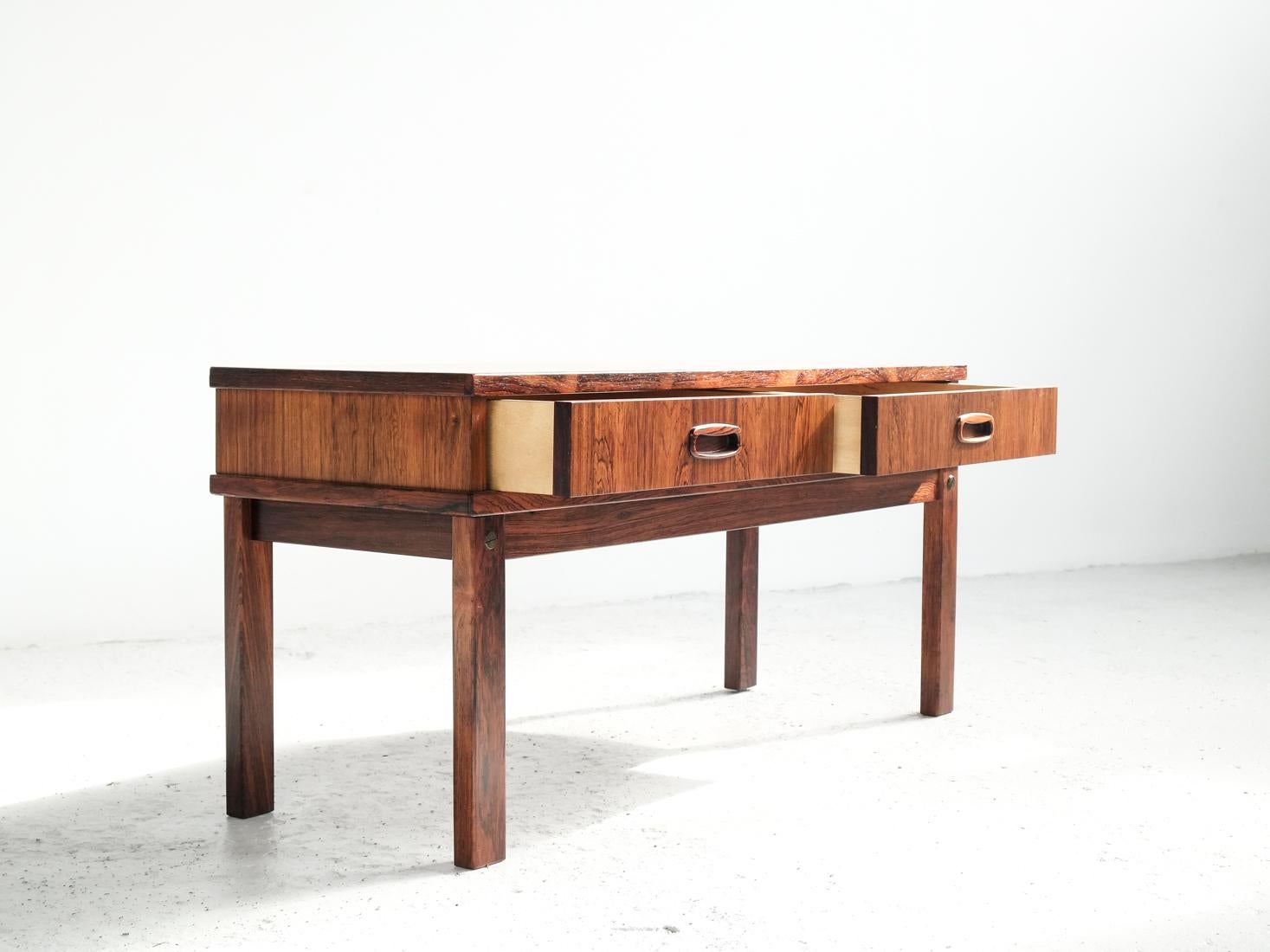 This midcentury Danish low chest of 2 drawers in rosewood was made in Denmark in the 1960s. It has beautiful drawings in the wood and is refined in every detail. It can be used as a low console table. This chest is in rosewood and in very good