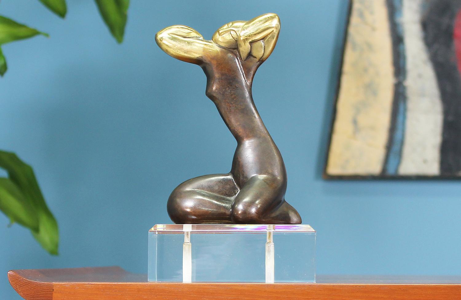 Abstract sculpture designed and manufactured in the United States circa 1960’s. This unique sculpture is composed of a brass abstract female silhouette over a lucite base showing minor wear consistent with age. The brass is beautifully patinated and