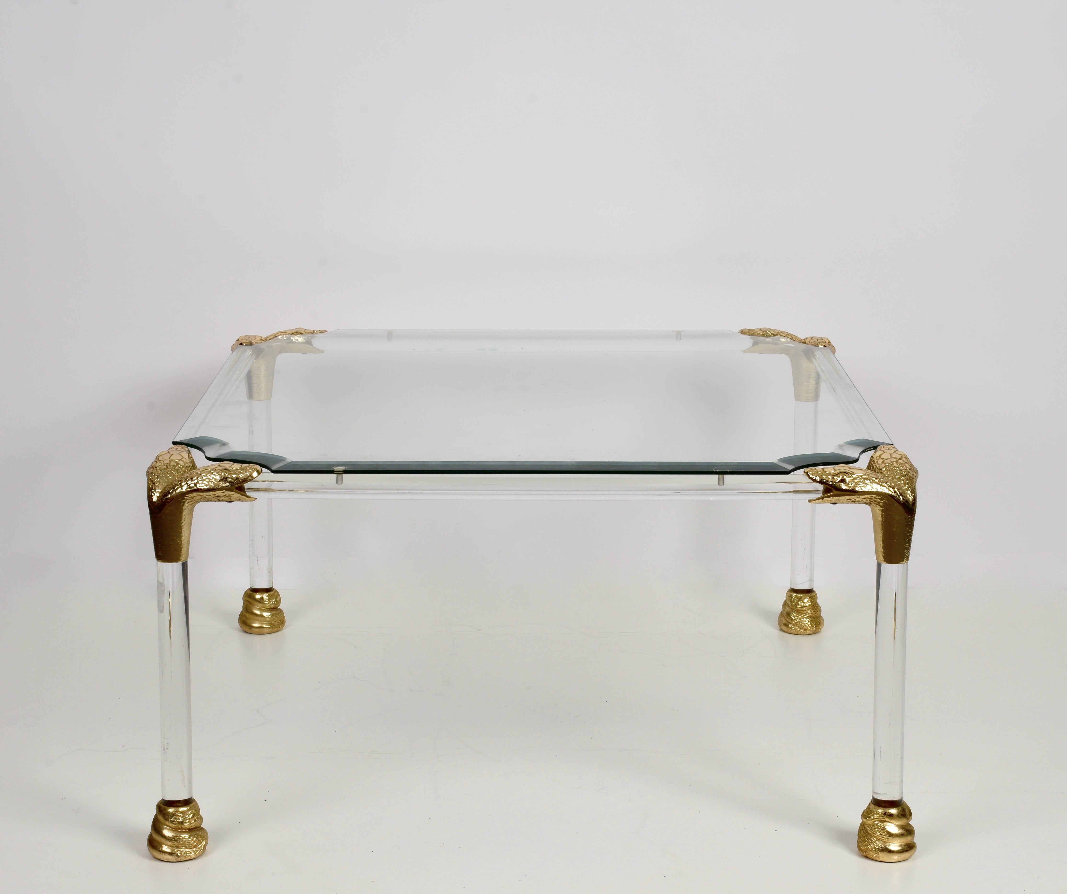 Midcentury Lucite and brass coffee table with snakehead details. This elegant item was designed during the 1970s in Italy.

This elegant cocktail table is marvelous as unique details like it has snakehead brass corners and brass snake bodies as