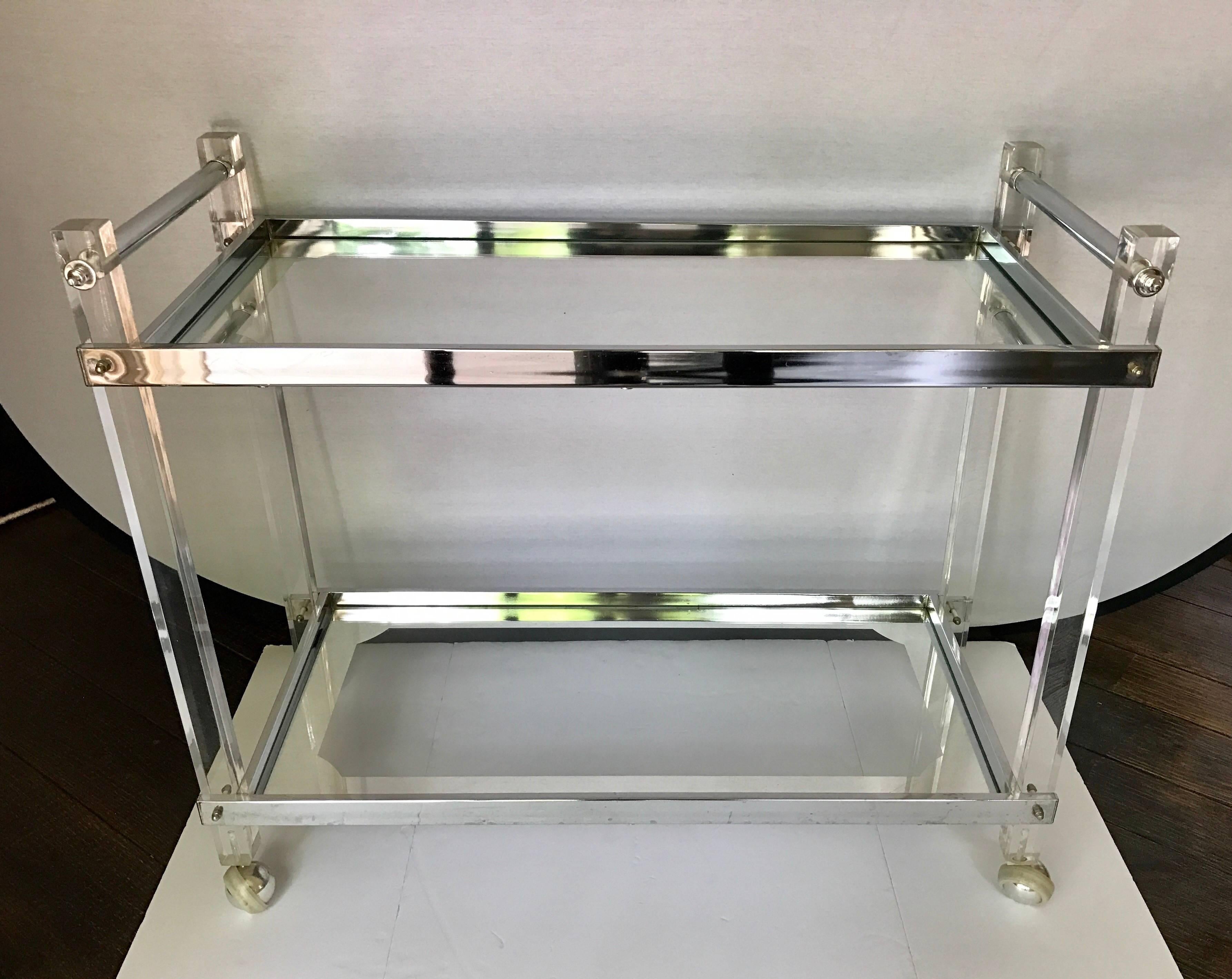 In the style of Charles Hollis Jones, this Italian lucite rolling bar cart will not disappoint.
Features glass inserts with etched silver boarders as well as chrome bracings.