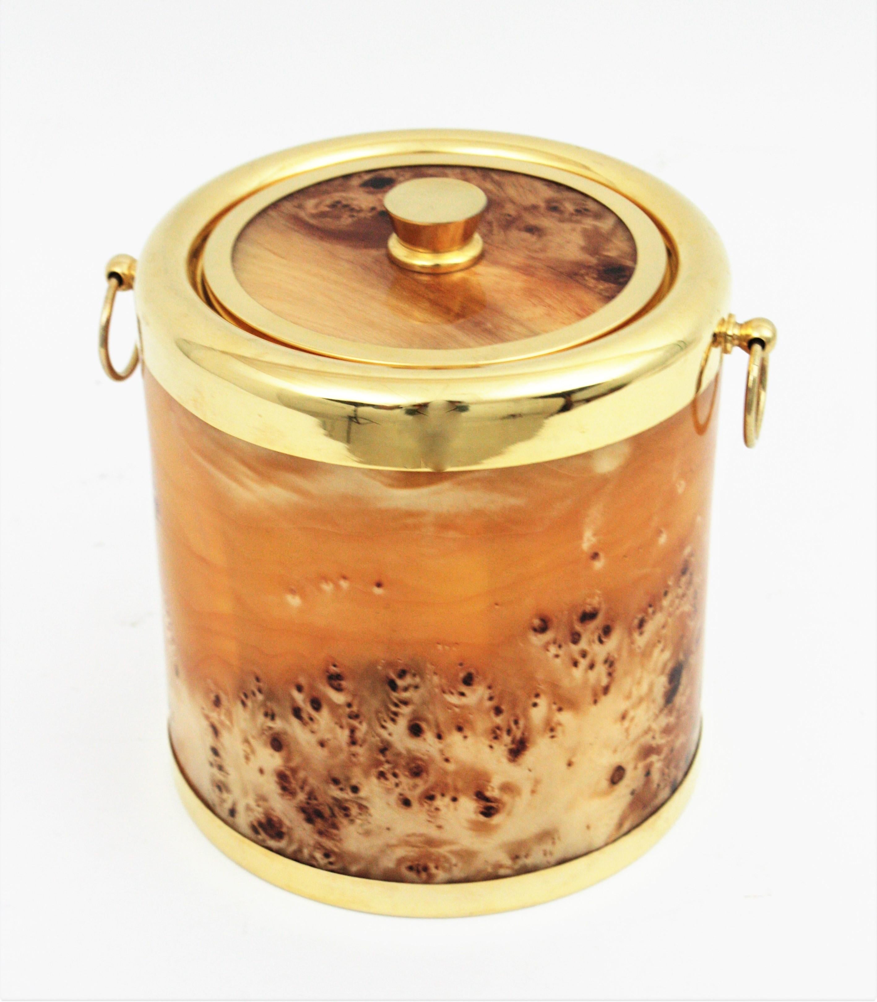Handsome Mid-Century Modern burl wood and metal ice bucket with handles. Italy, 1960s.
This ice bucket is comprised by a cylindrical container with lid, covered with burl wood and lucite and ring handles at both sides. It has accents in