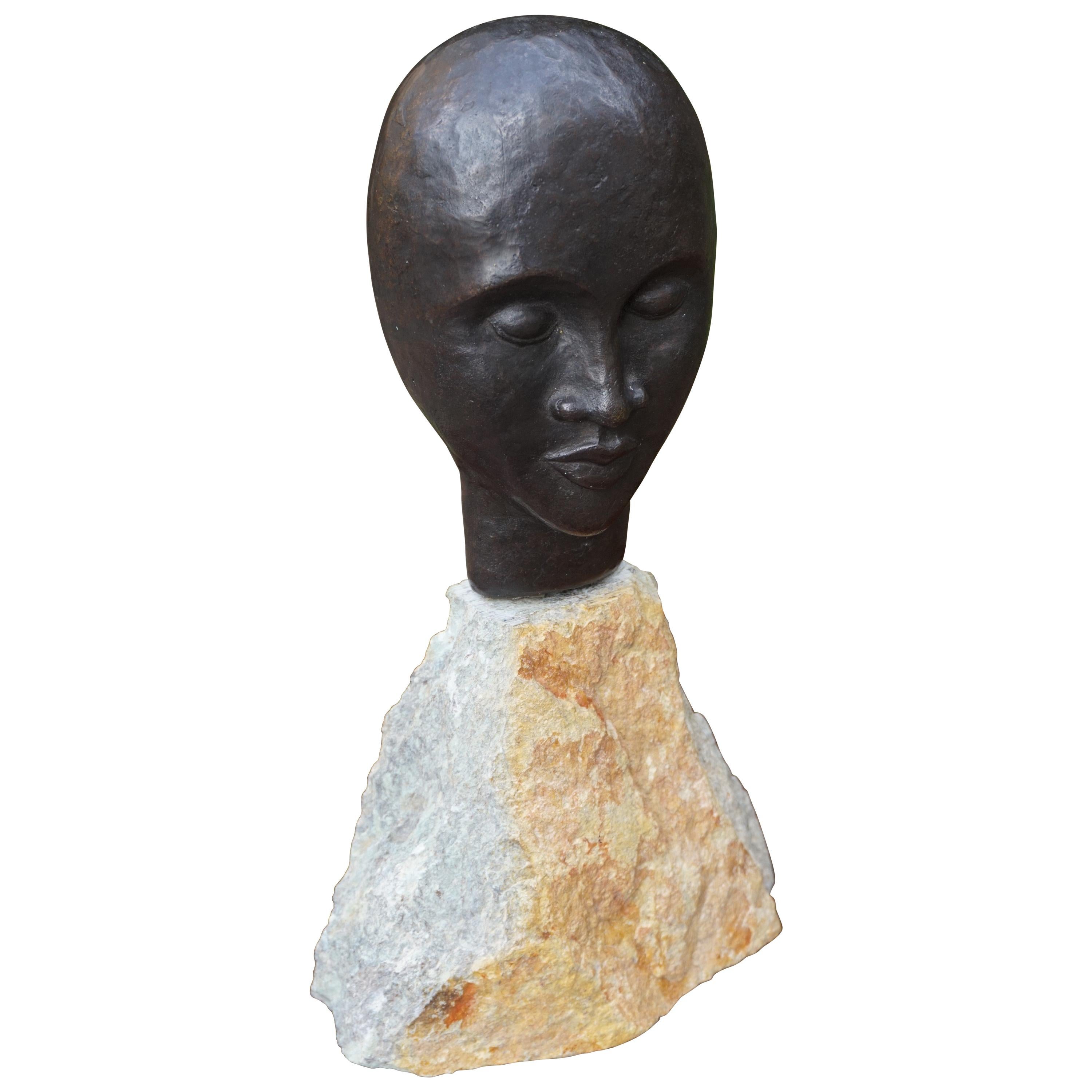 Sculpture en bronze d'un homme africain serein réalisée au milieu du siècle dernier sur un socle en pierre calcaire en vente