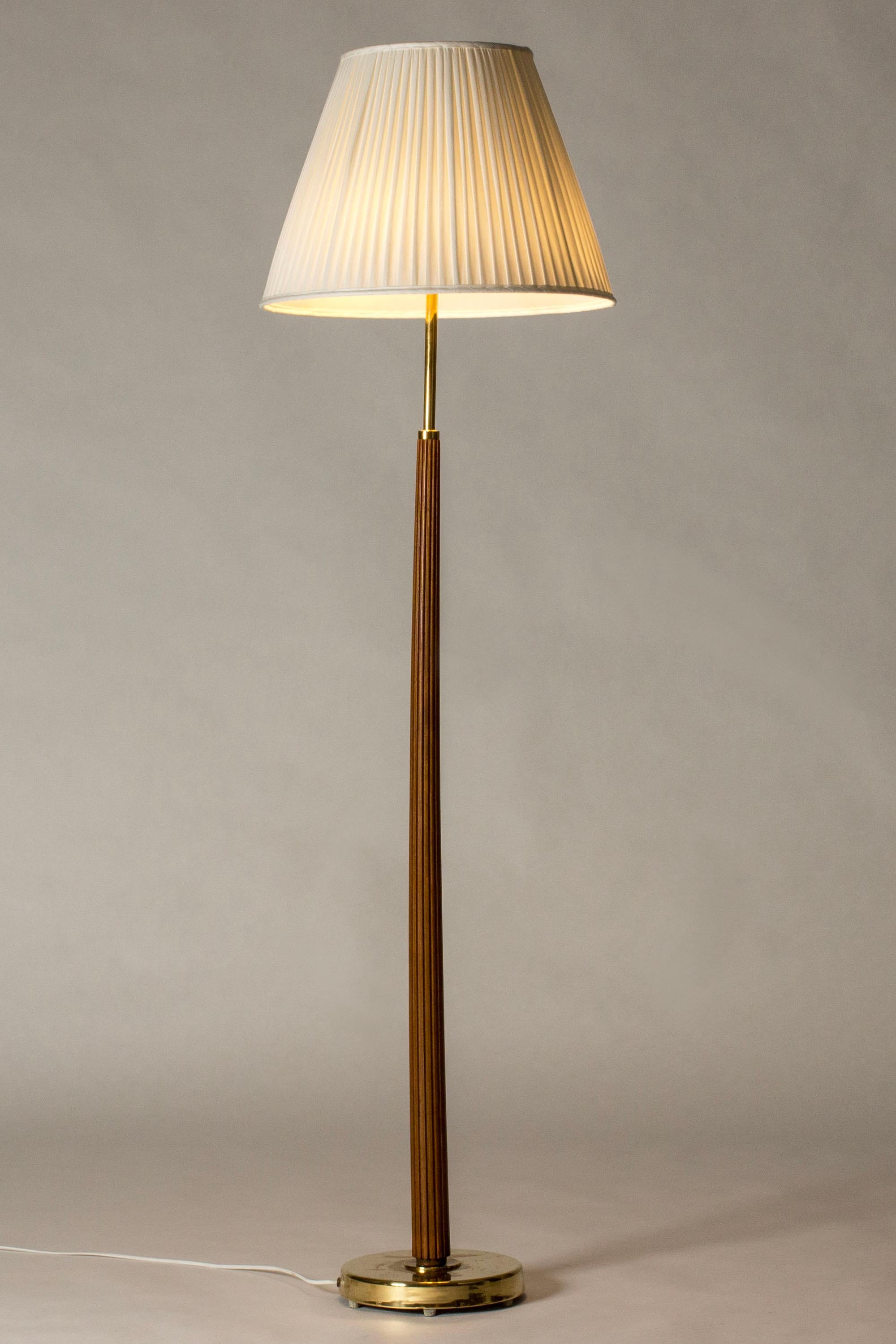 Lampadaire de Hans Bergström, en laiton avec une tige en acajou. Design/One élégant avec de jolis détails, bandes gaufrées dans le bois, abat-jour plissé.