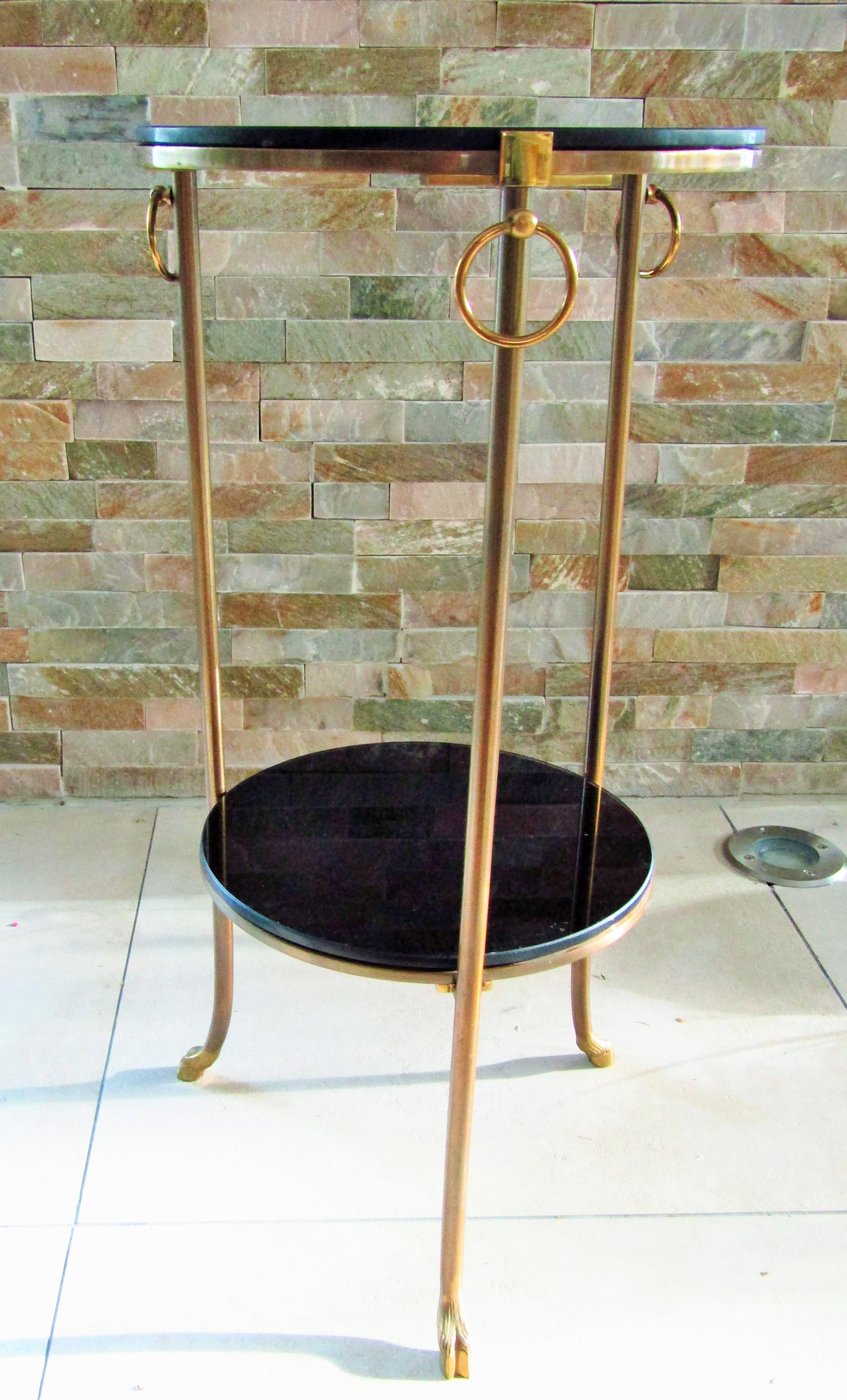 A midcentury side table signed Maison Charles, France, circa 1960. Two black glass tops, supported by three brass legs detailed with movable rings and hooved goat feet.

 
