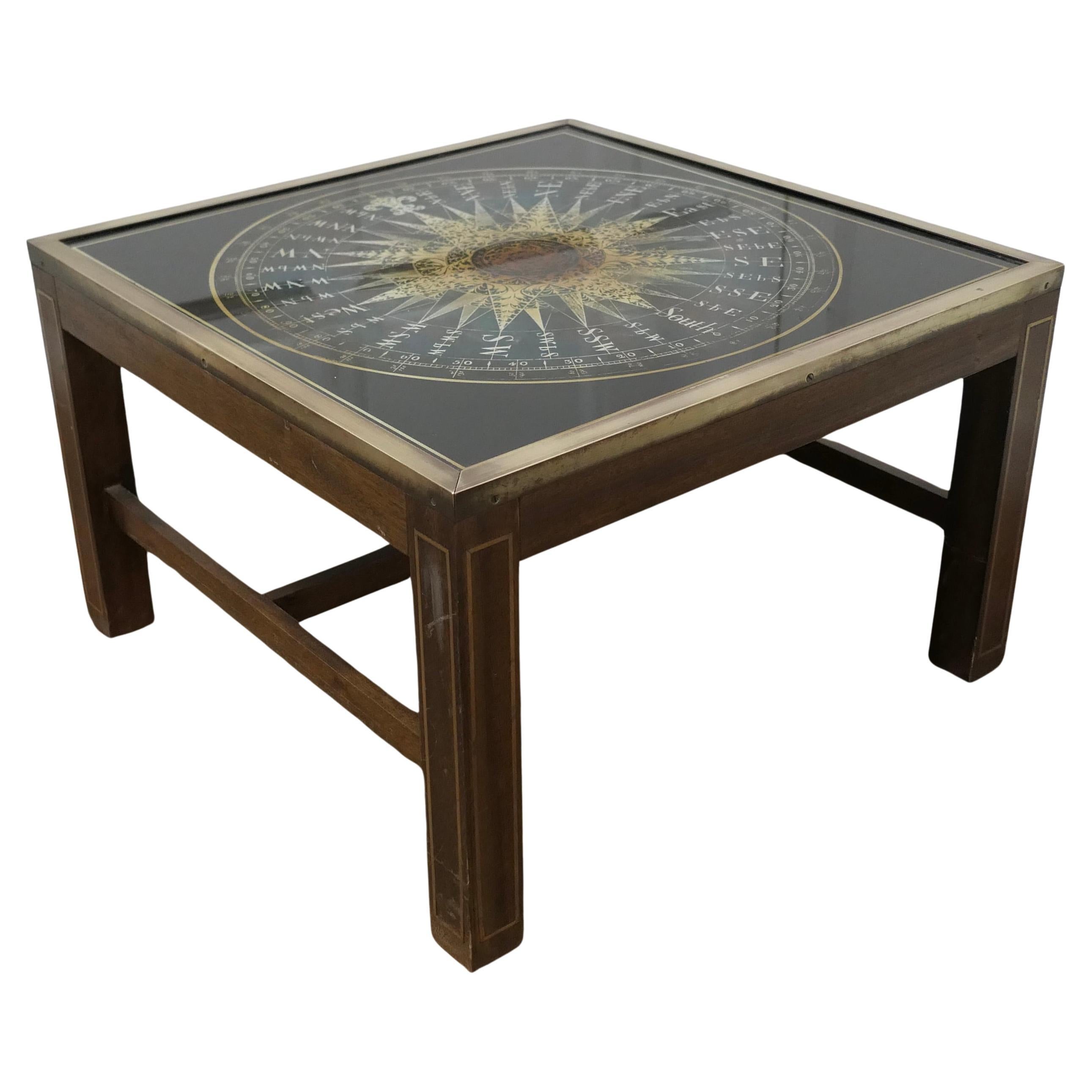 Midcentury Maison Jansen Campaign Style Coffee Table

A Cube Coffee table, the base has brass trim and inlay, the top is a reverse painted glass in black and gold with an English drawing of a compass by Samuel Dunn Clements Inn 1774
This superb