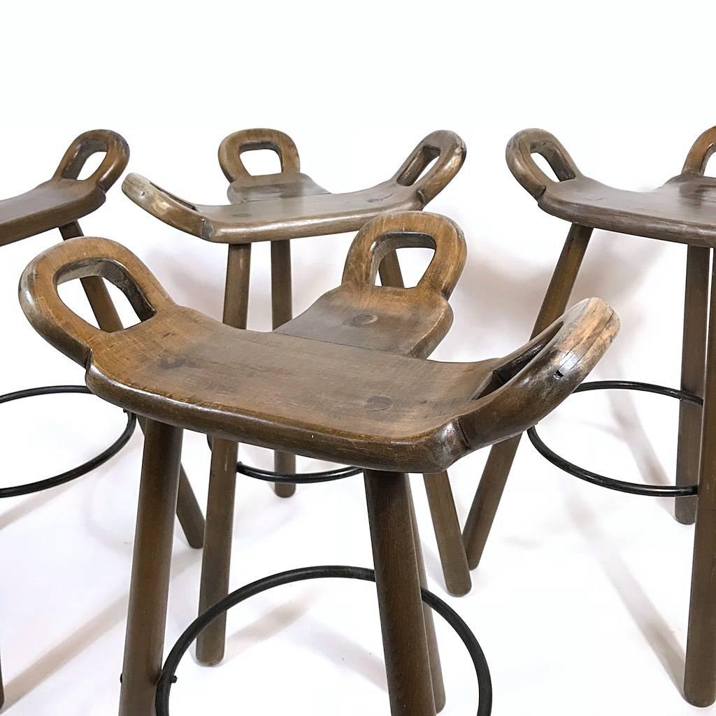 Four Marbella bar stools in stained oak wood and with a metal ring in the style of Sergio Rodrigues. The curved T-shape seat makes the seating very comfortable. The three handles are very functional for moving on and off.

Measurements: 
H 83 cm