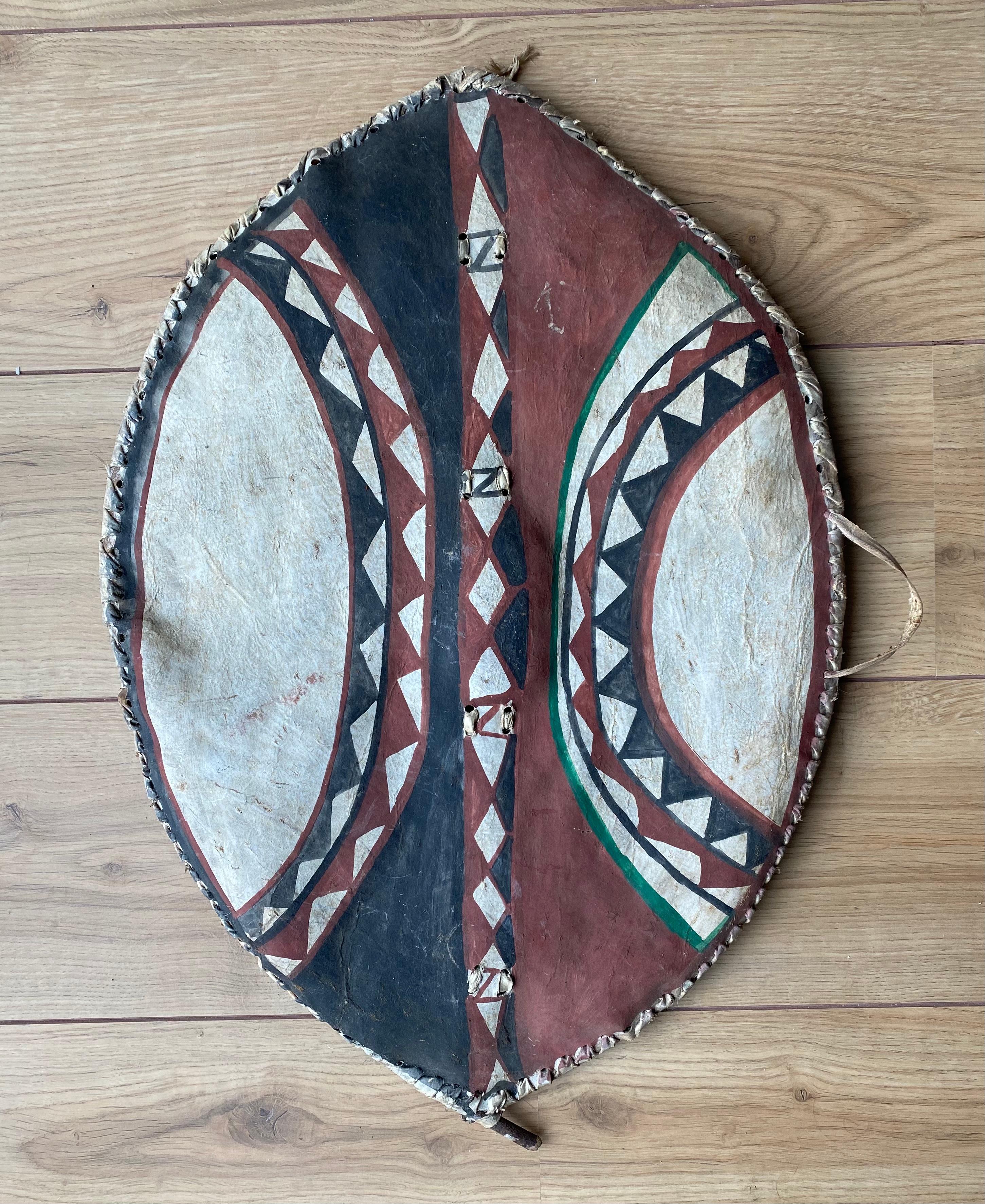 Masai Shield hand painted with pigments on (Cow)hide. This stunning elliptical graphic shield was probably owned by a warrior herder as younger warriors were only permitted to have black, white or gray pigments to decorate their shields. The red
