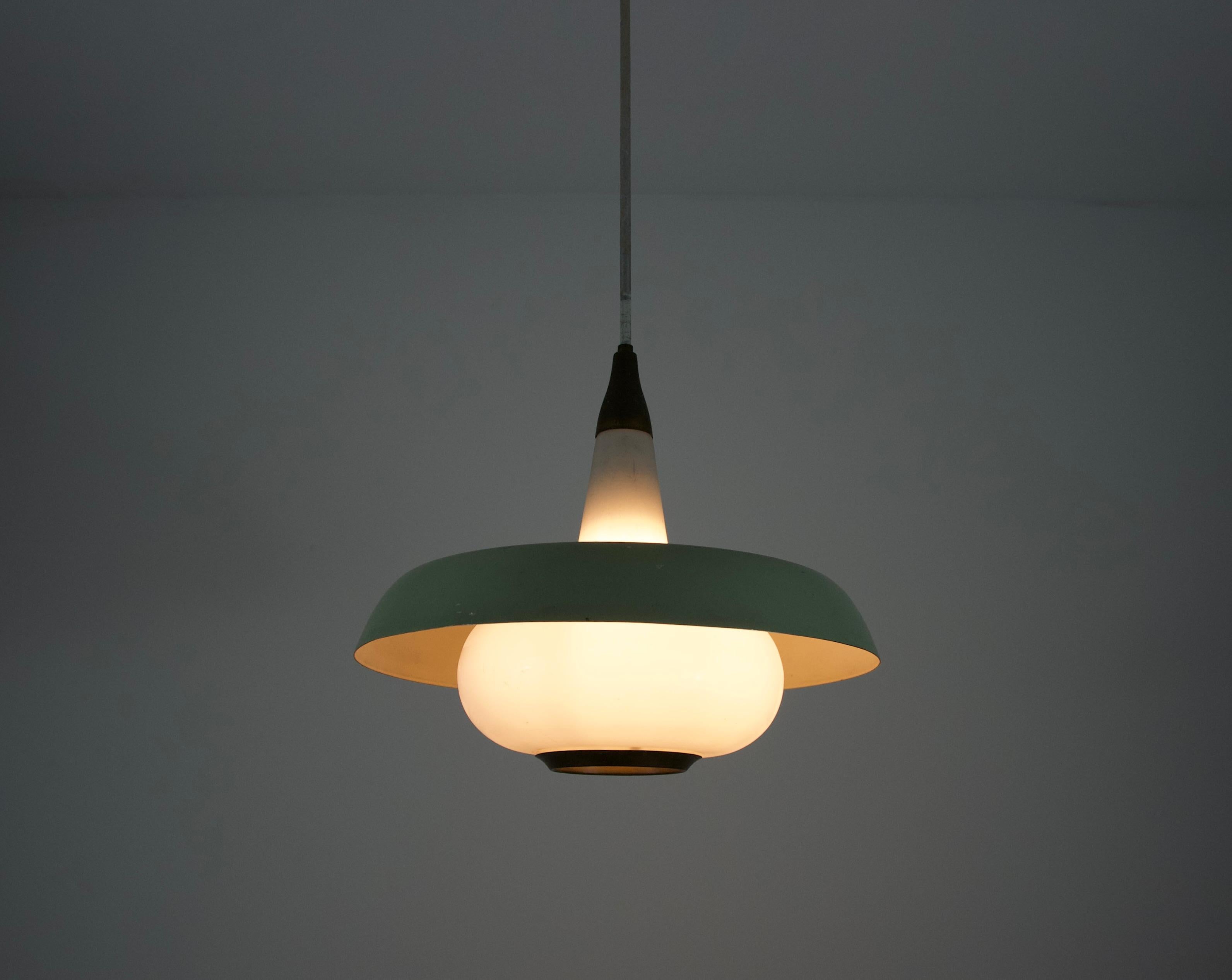 Cette élégante lampe suspendue du milieu du siècle, originaire de l'Italie des années 1960, présente l'équilibre raffiné entre la forme et la fonction, caractéristique du design de l'époque. La lampe combine le métal peint et le verre opale, ce qui