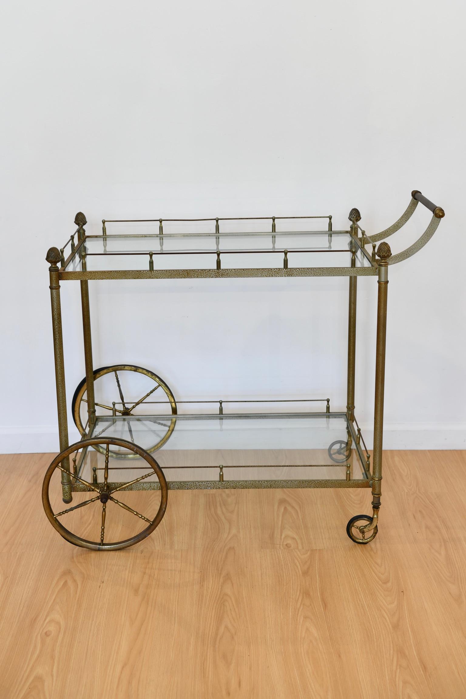 Pantinaed midcentury metal bar cart on wheels. Small chip to glass on bottom shelf, pictured. Wheels in vintage condition but functional. Dimensions: 33