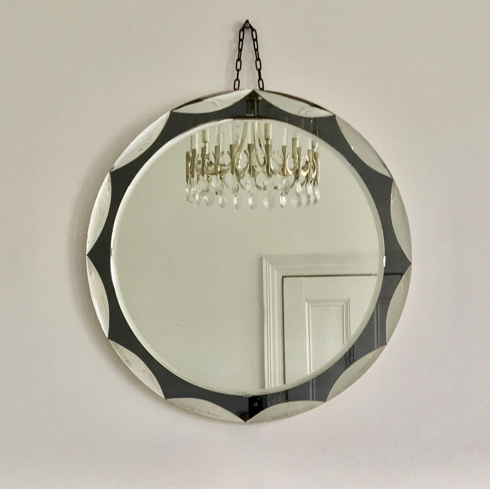 Midcentury circular mirror with large scalloped black glass edge detail. Metalvetro Galvorame of Siena, 1960s, Italy.

The mirror is a high-quality piece, of good size, with a double layer of mirror glass. The central glass is clear, with a beveled