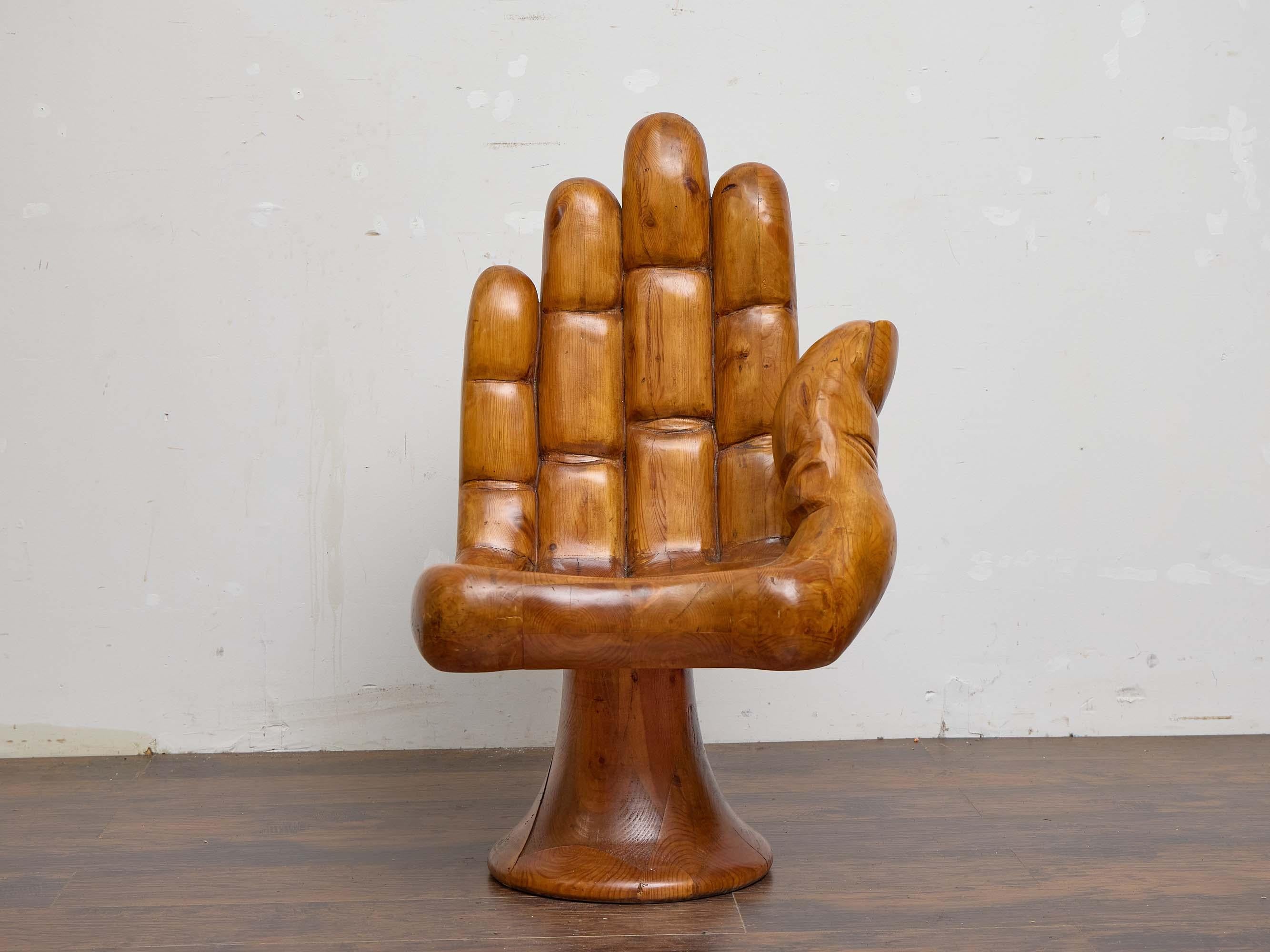 Sculptural and playful, this midcentury Mexican hand chair offers a bold, artistic presence with practical seating comfort. Carved from solid pine, the chair is shaped in the form of an upright hand, with the palm and fingers forming the seat and