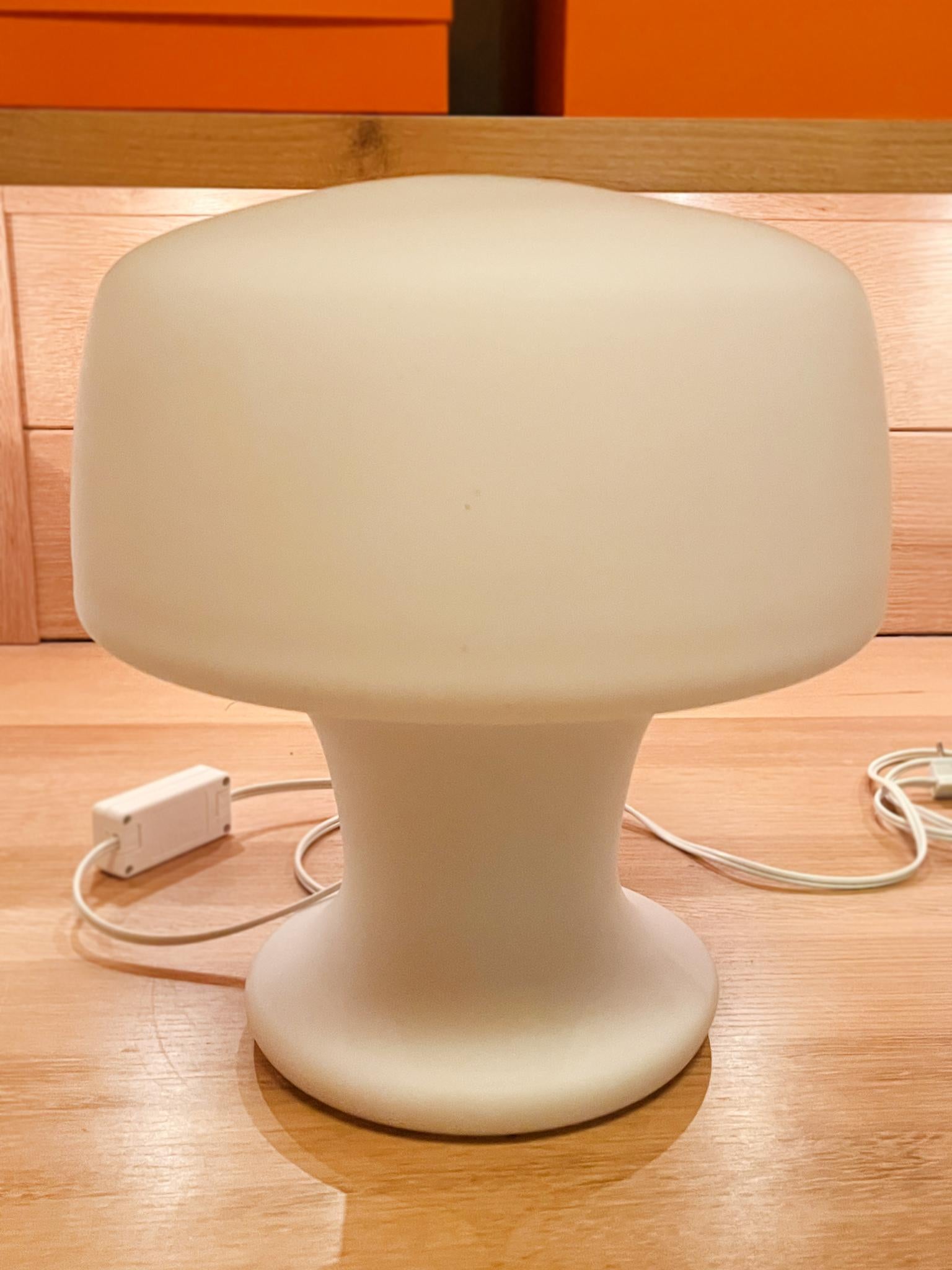 Made in the Mid-20th Century, this charming mushroom-shaped table lamp consists of milk glass. It has been newly rewired with a single bulb socket and furbished with a dimmer switch on the cord. Elegant and minimalist in design, when lit, it's as if